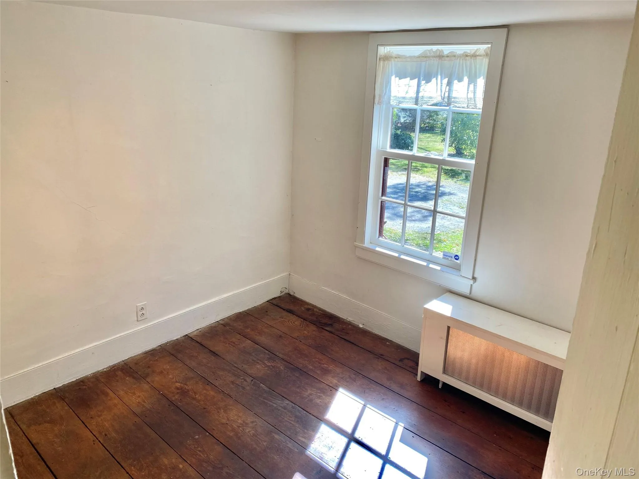 Spare room with radiator and dark wood-style floors Spare room with radiator and dark wood-style floors