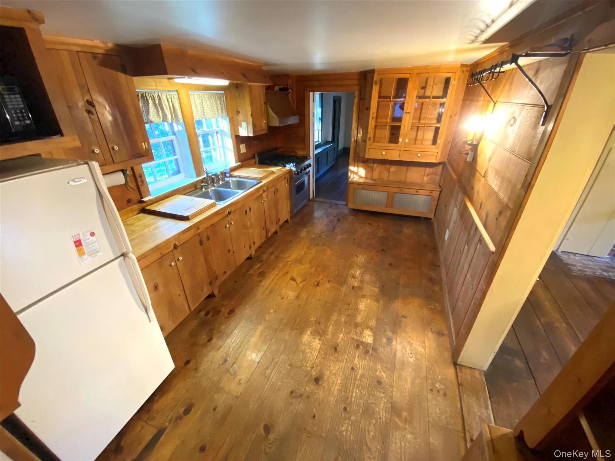 Kitchen featuring freestanding refrigerator, light countertops, dark wood finished floors, high end stainless steel range, and brown cabinets Kitchen featuring freestanding refrigerator, light countertops, dark wood finished floors, high end stainless steel range, and brown cabinets