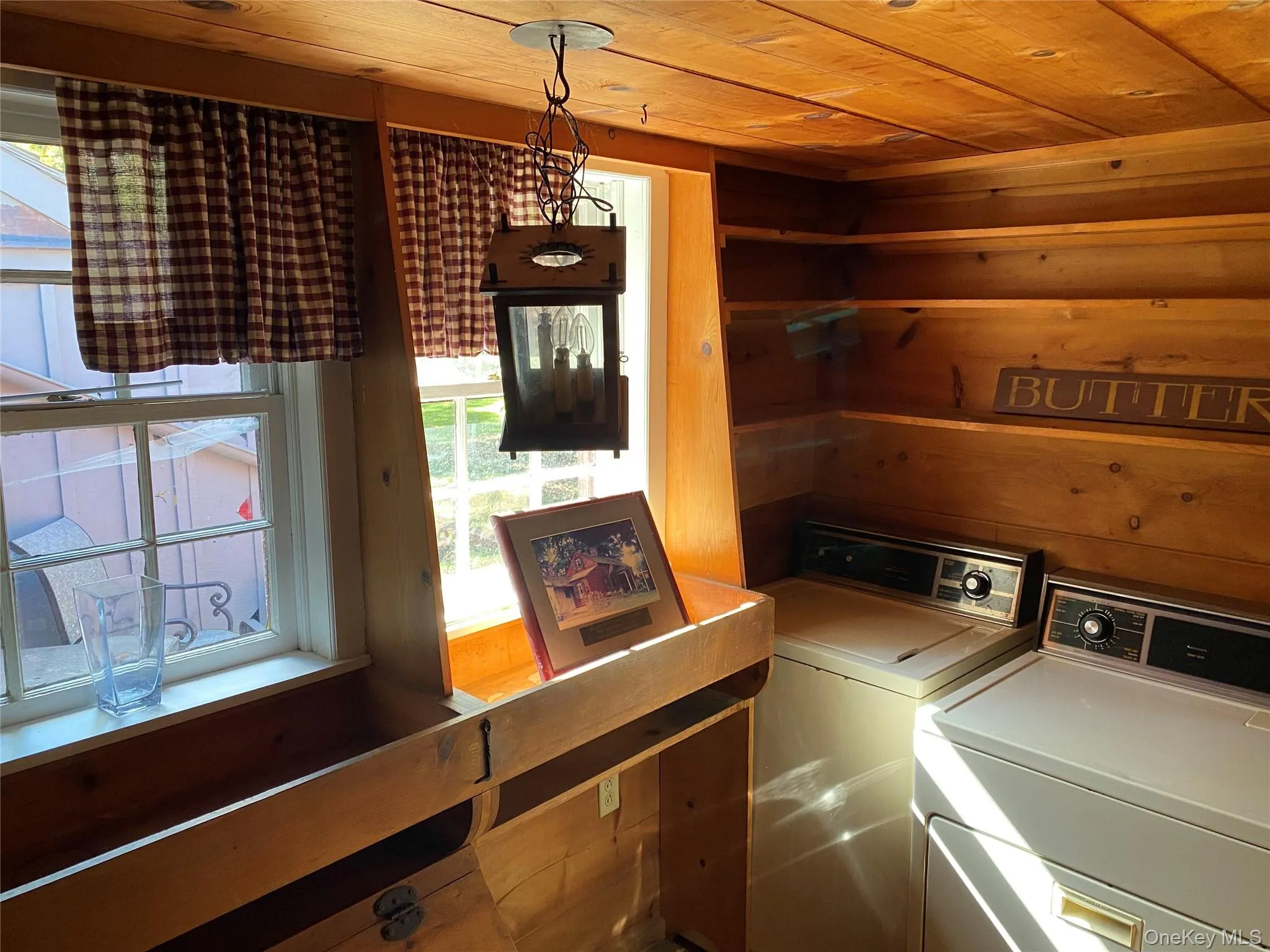 Laundry area featuring wood walls, wooden ceiling, and washing machine and dryer Laundry area featuring wood walls, wooden ceiling, and washing machine and dryer