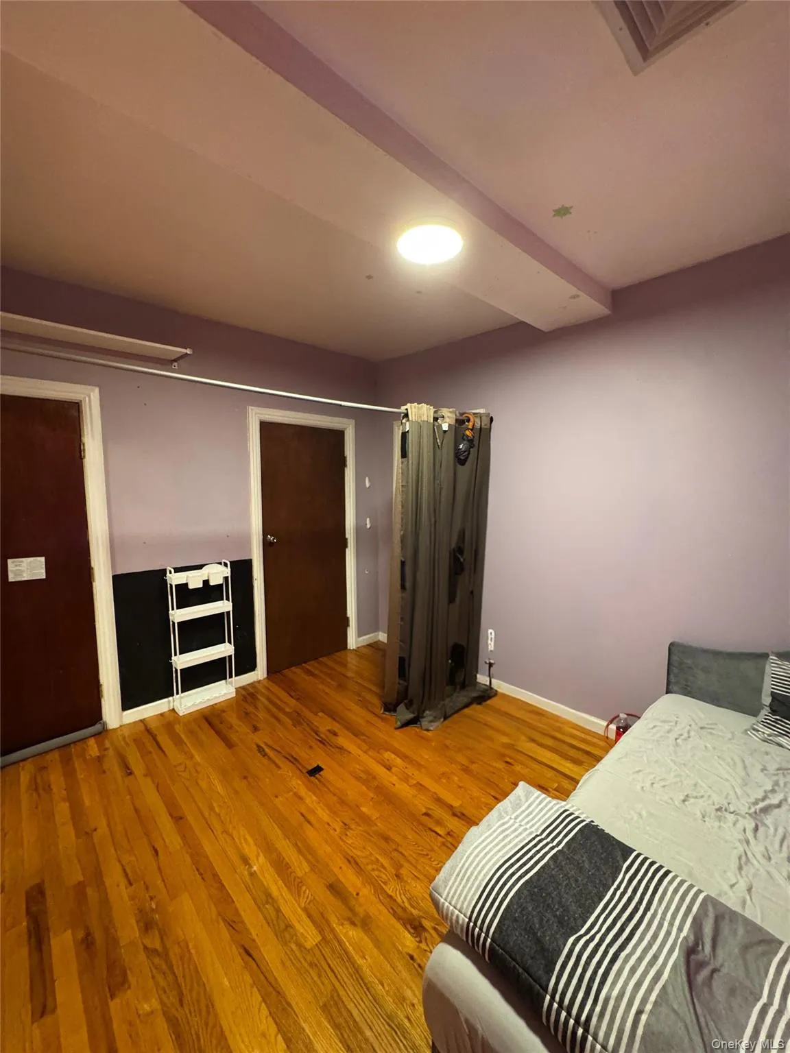 Bedroom featuring attic access, light wood finished floors, and beamed ceiling Bedroom featuring attic access, light wood finished floors, and beamed ceiling