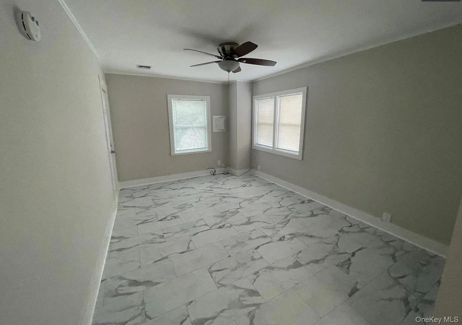 Spare room with light marble finish floors, crown molding, and a smoke detector Spare room with light marble finish floors, crown molding, and a smoke detector