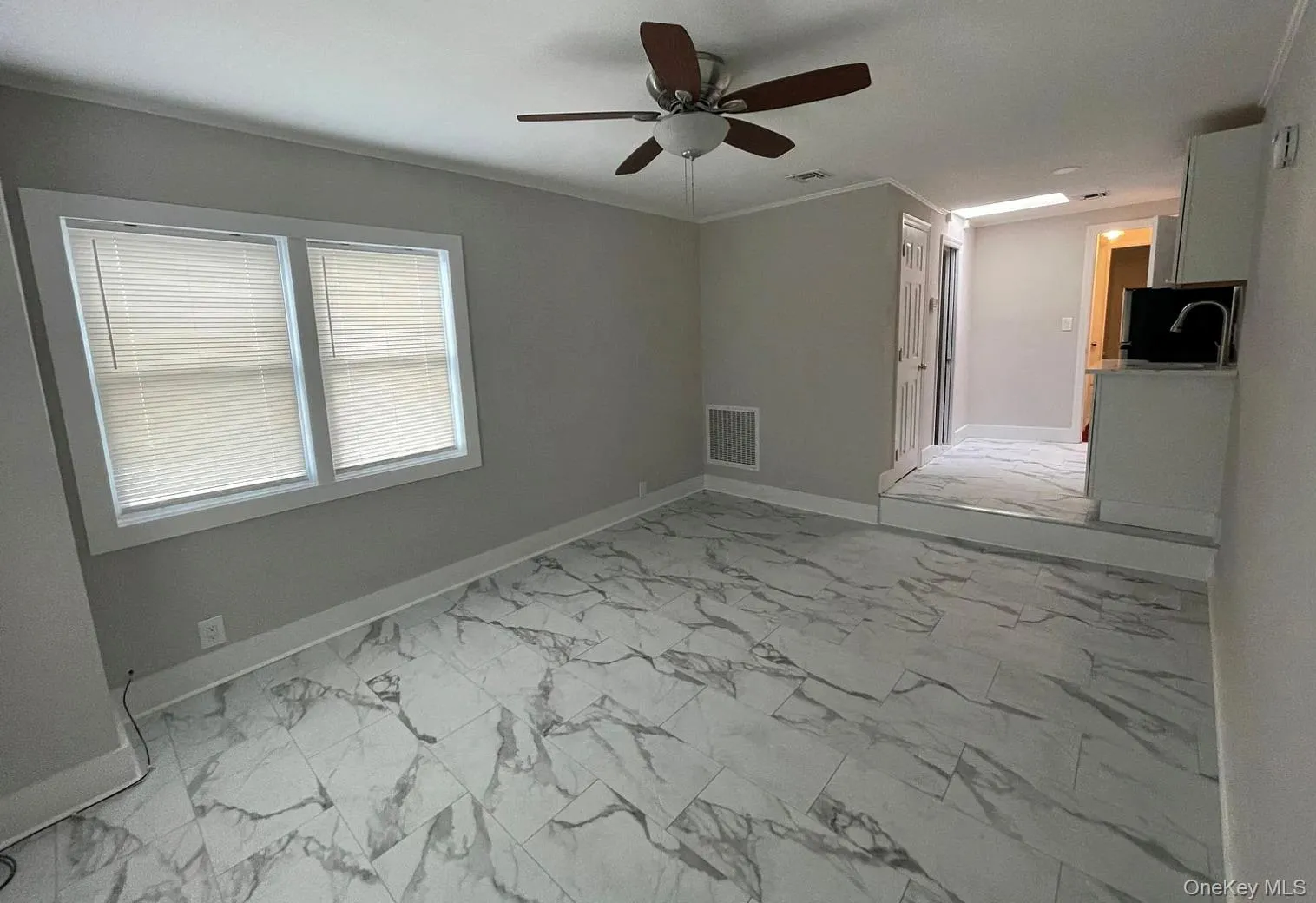 Empty room featuring light marble finish floors and ornamental molding Empty room featuring light marble finish floors and ornamental molding