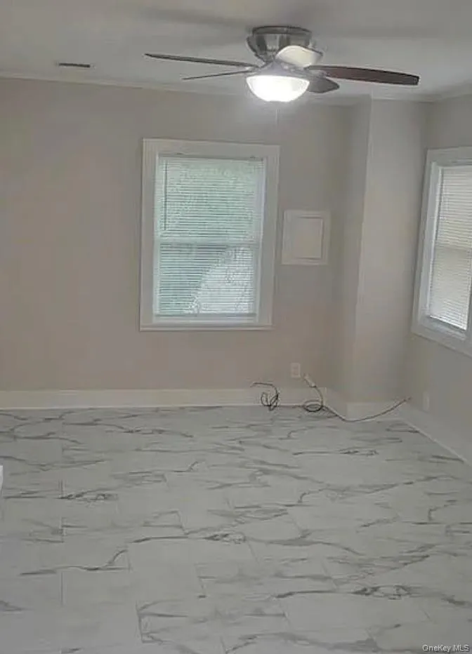 Unfurnished room featuring a ceiling fan, crown molding, and light marble finish floors Unfurnished room featuring a ceiling fan, crown molding, and light marble finish floors