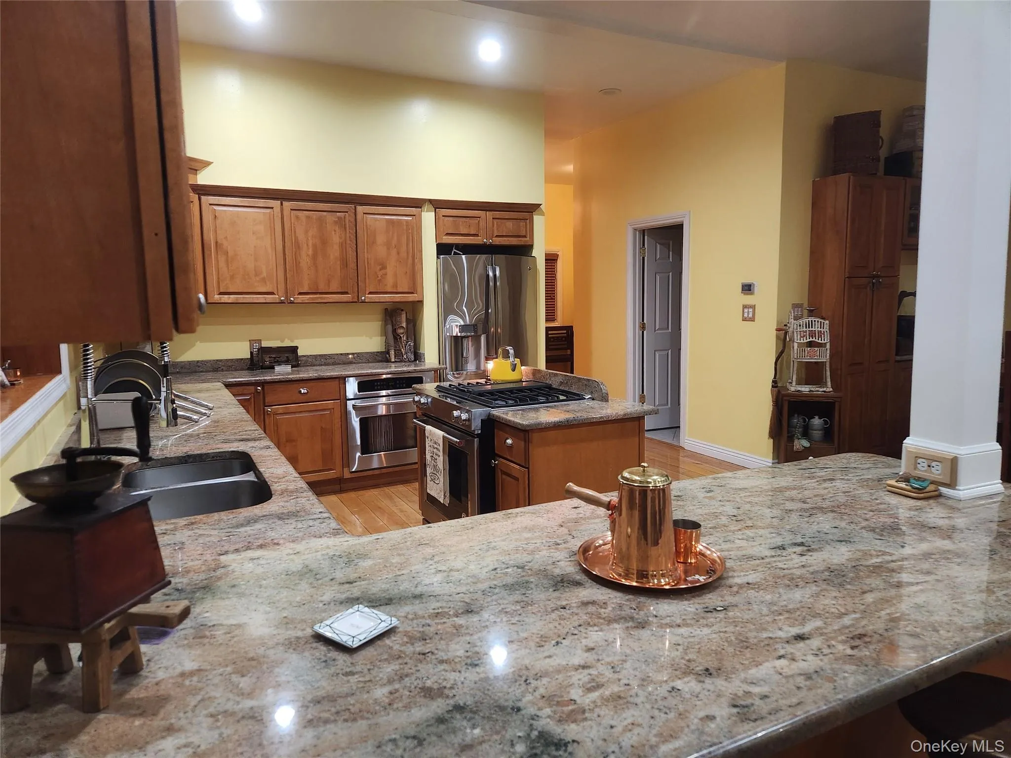Kitchen featuring sink, a center island, stainless steel appliances, light stone countertops, and light hardwood / wood-style floors Kitchen featuring sink, a center island, stainless steel appliances, light stone countertops, and light hardwood / wood-style floors