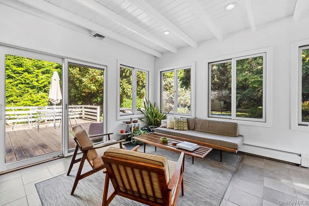 Sunroom / solarium featuring a baseboard radiator, tile patterned flooring, plenty of natural light, beamed ceiling, and recessed lighting Sunroom / solarium featuring a baseboard radiator, tile patterned flooring, plenty of natural light, beamed ceiling, and recessed lighting