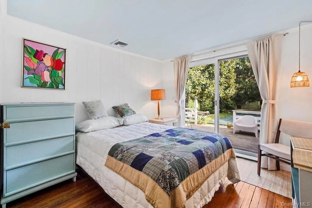 Bedroom with wood-type flooring, access to exterior, ornamental molding, and wood walls Bedroom with wood-type flooring, access to exterior, ornamental molding, and wood walls
