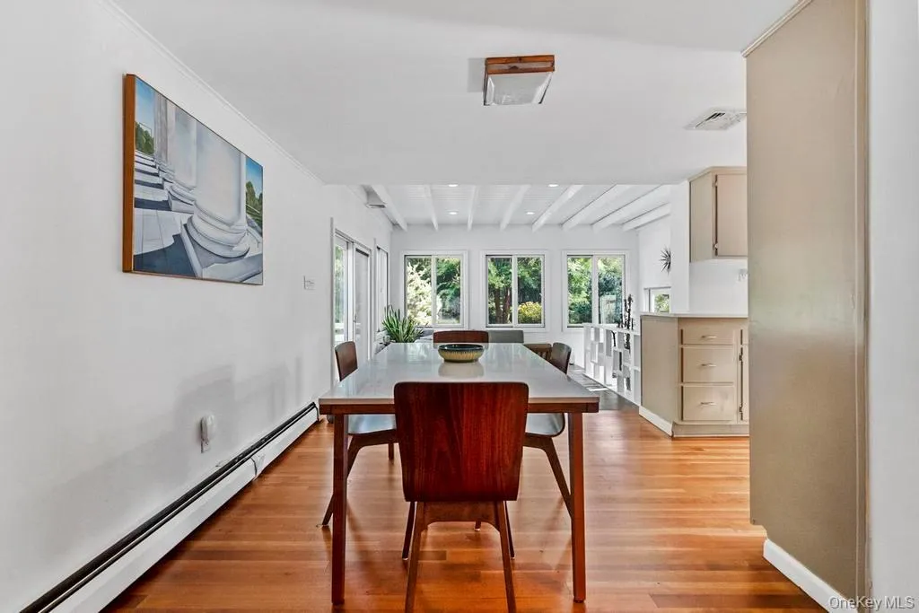 Dining room with beamed ceiling, a baseboard heating unit, and light wood-style flooring Dining room with beamed ceiling, a baseboard heating unit, and light wood-style flooring