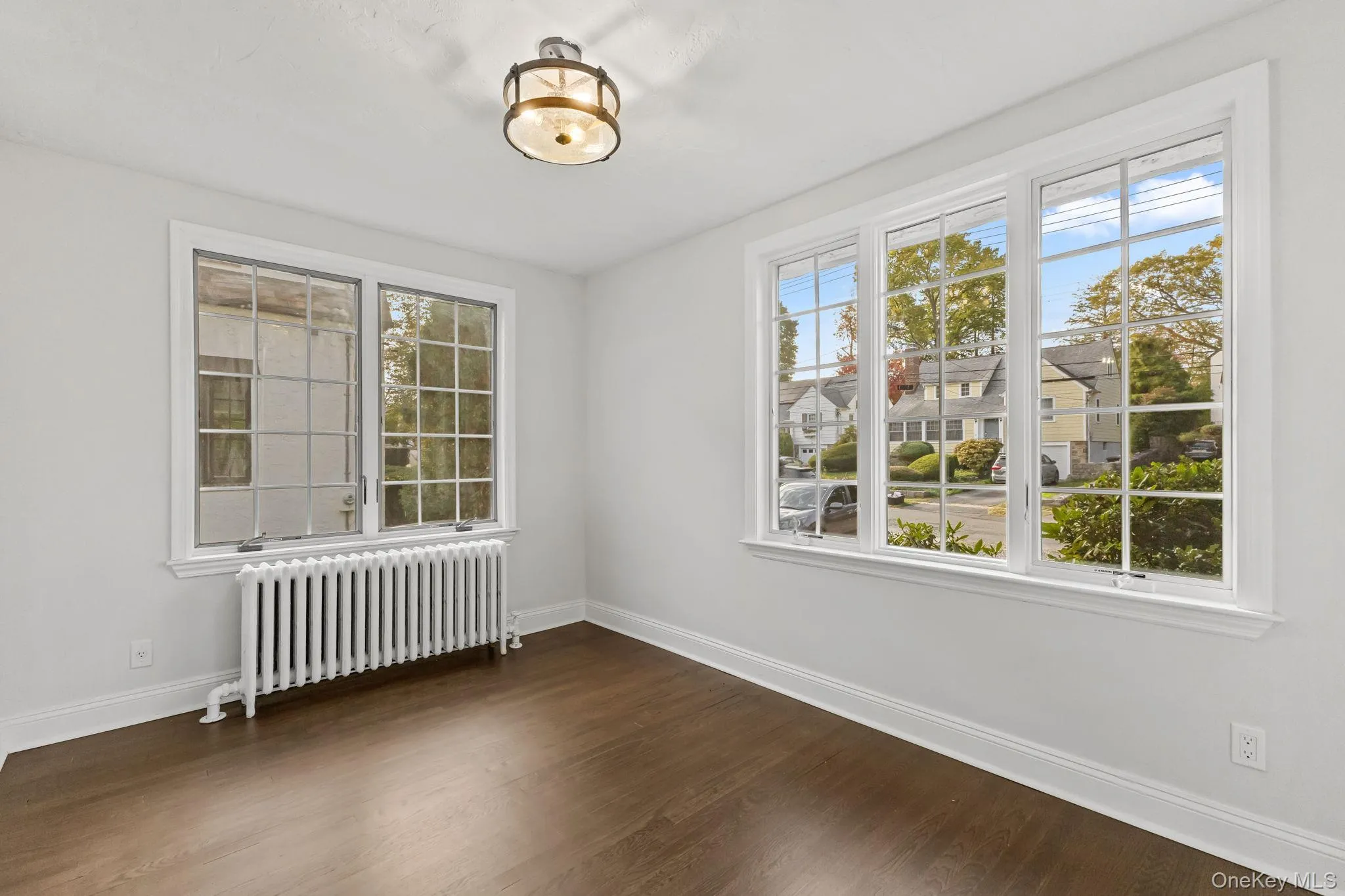 Unfurnished room with radiator and dark wood-type flooring Unfurnished room with radiator and dark wood-type flooring