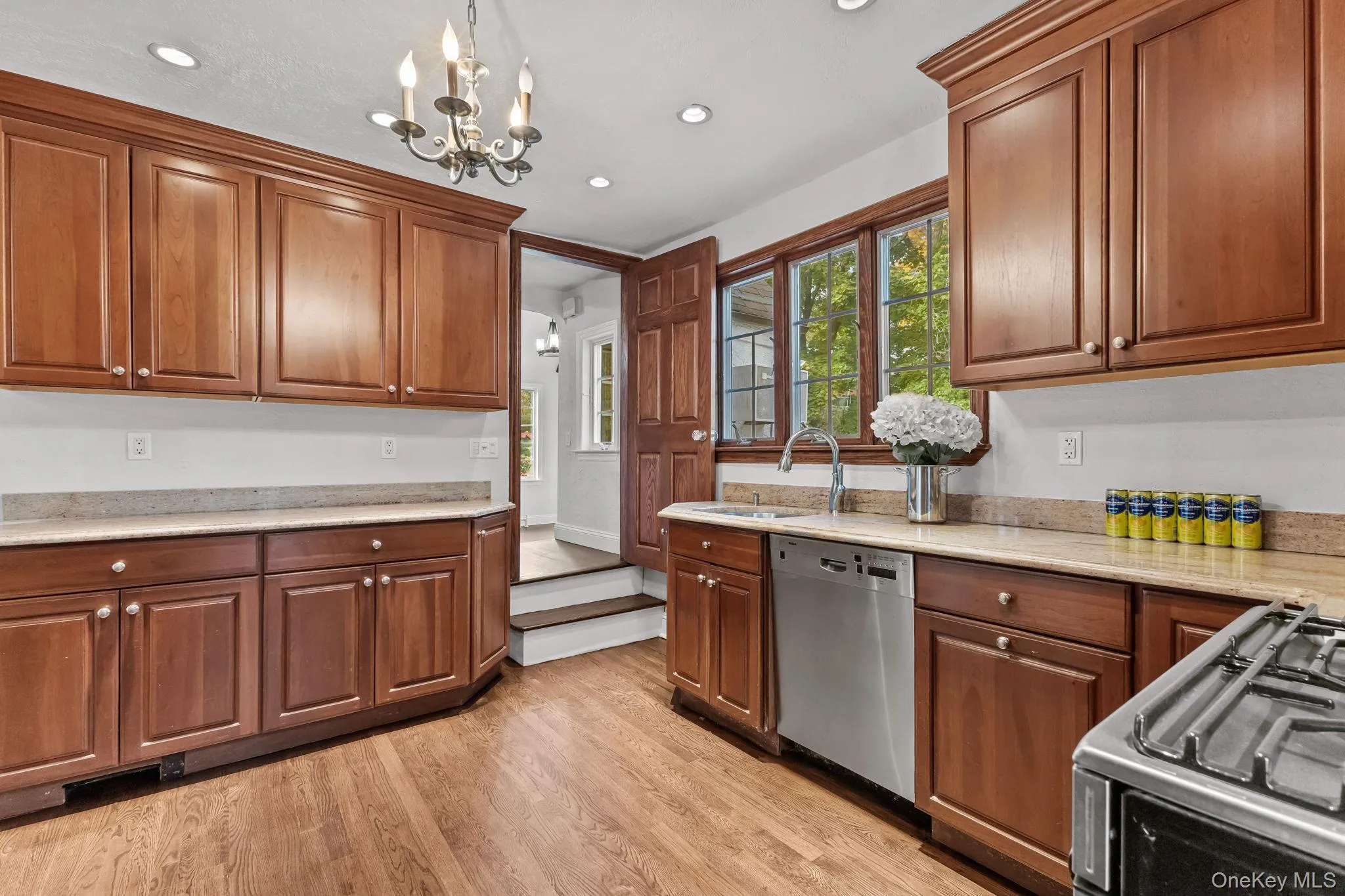 Kitchen featuring stainless steel appliances, light wood finished floors, a chandelier, light stone countertops, and recessed lighting Kitchen featuring stainless steel appliances, light wood finished floors, a chandelier, light stone countertops, and recessed lighting