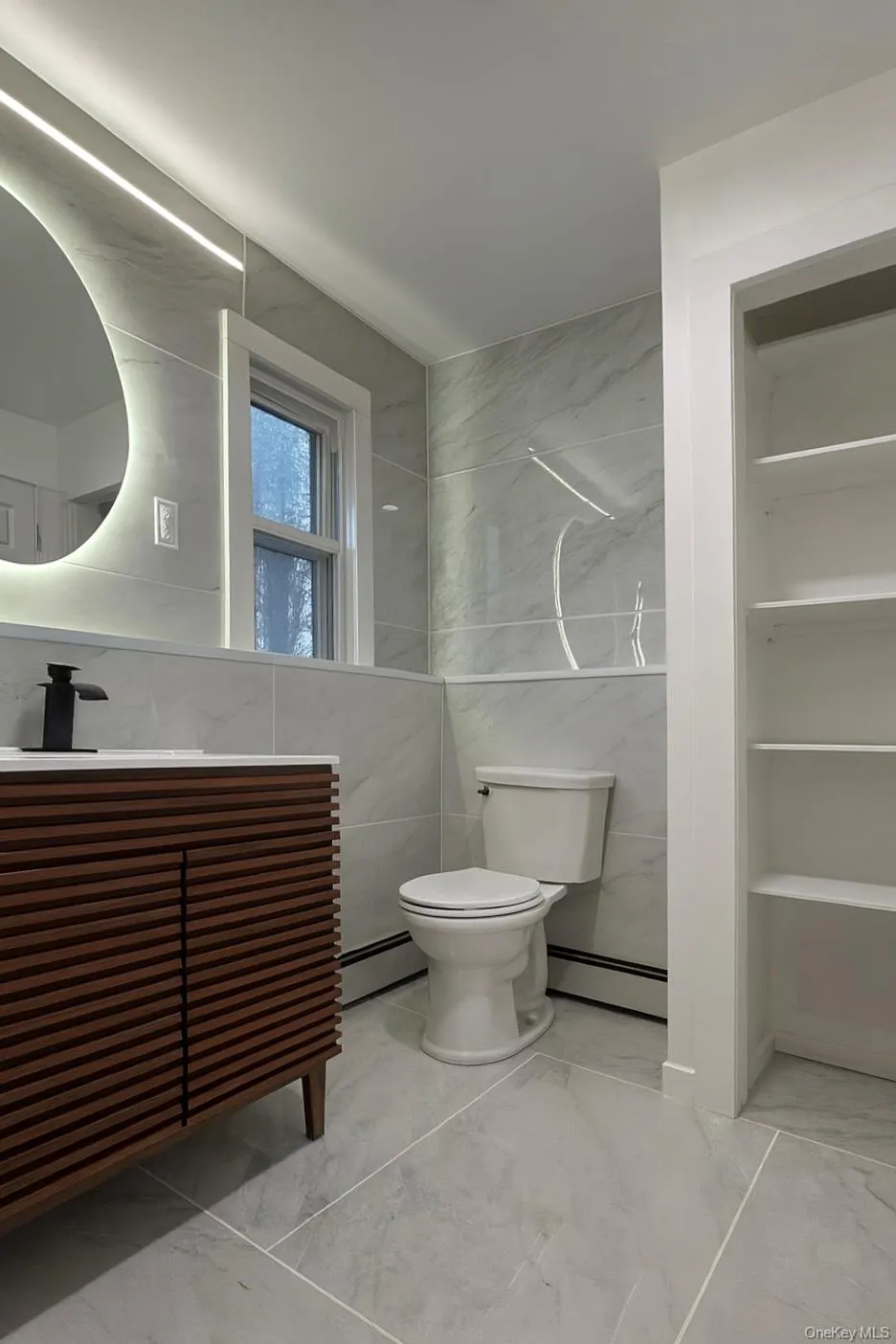 Main level bathroom with tile walls, marble finish floors, a baseboard radiator, and vanity Main level bathroom with tile walls, marble finish floors, a baseboard radiator, and vanity