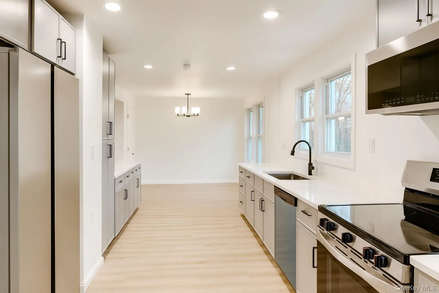Kitchen featuring stainless steel appliances, recessed lighting, pendant lighting, light wood-style floors, and light stone counters Kitchen featuring stainless steel appliances, recessed lighting, pendant lighting, light wood-style floors, and light stone counters
