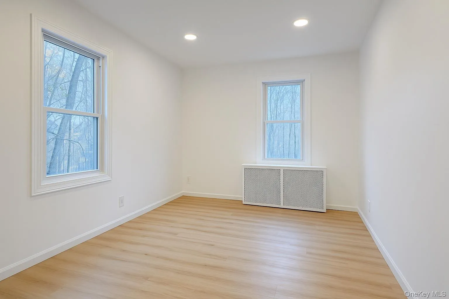 Ground level bedroom with radiator, light wood-style flooring, and recessed lighting Ground level bedroom with radiator, light wood-style flooring, and recessed lighting