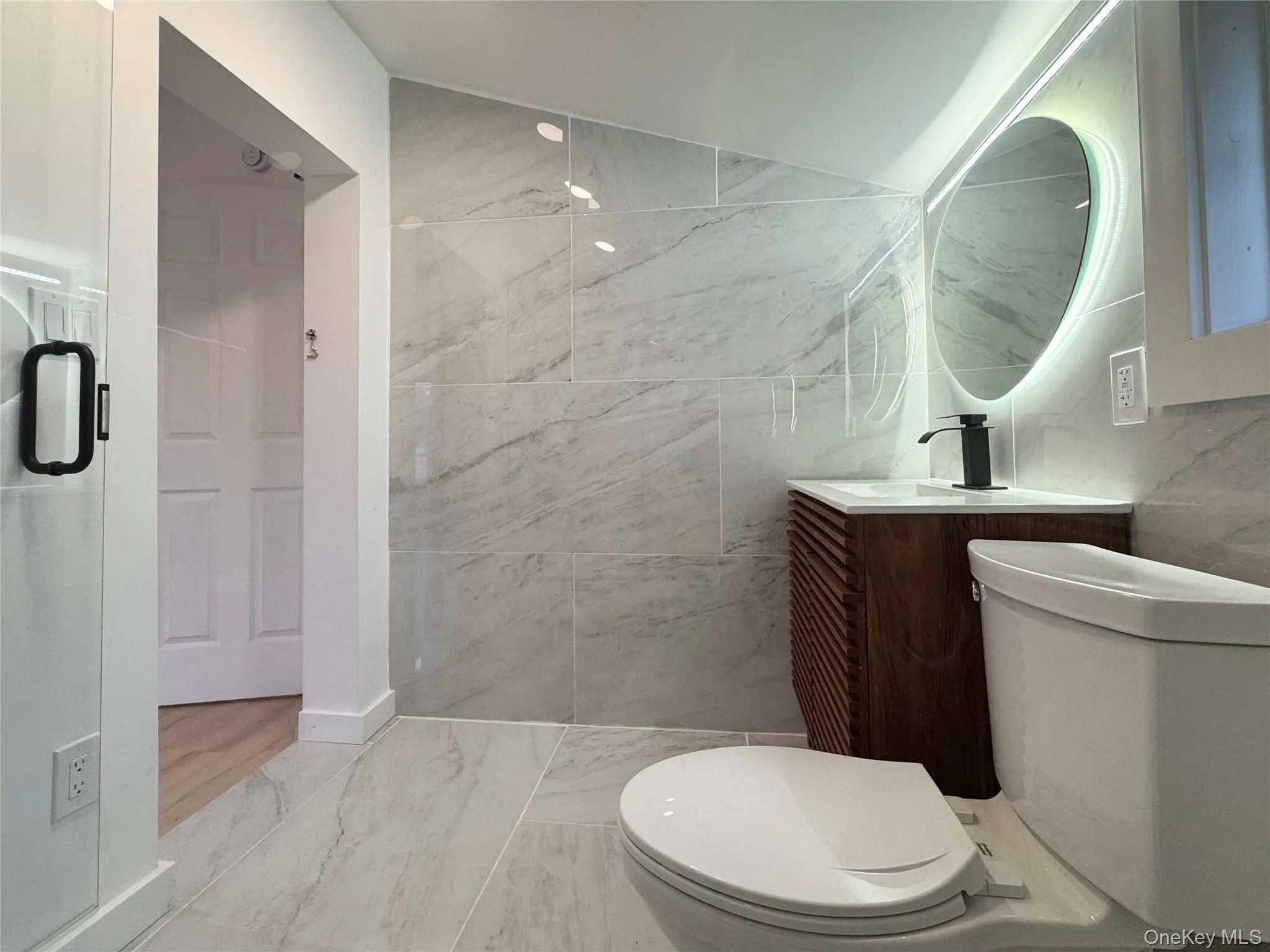Bathroom with vanity, marble look tile flooring, and tile walls Bathroom with vanity, marble look tile flooring, and tile walls