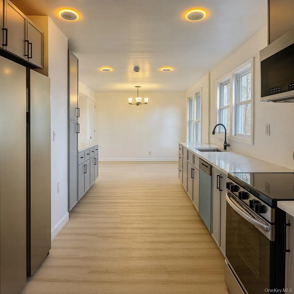 Kitchen featuring appliances with stainless steel finishes, light wood finished floors, gray cabinetry, and hanging light fixtures Kitchen featuring appliances with stainless steel finishes, light wood finished floors, gray cabinetry, and hanging light fixtures