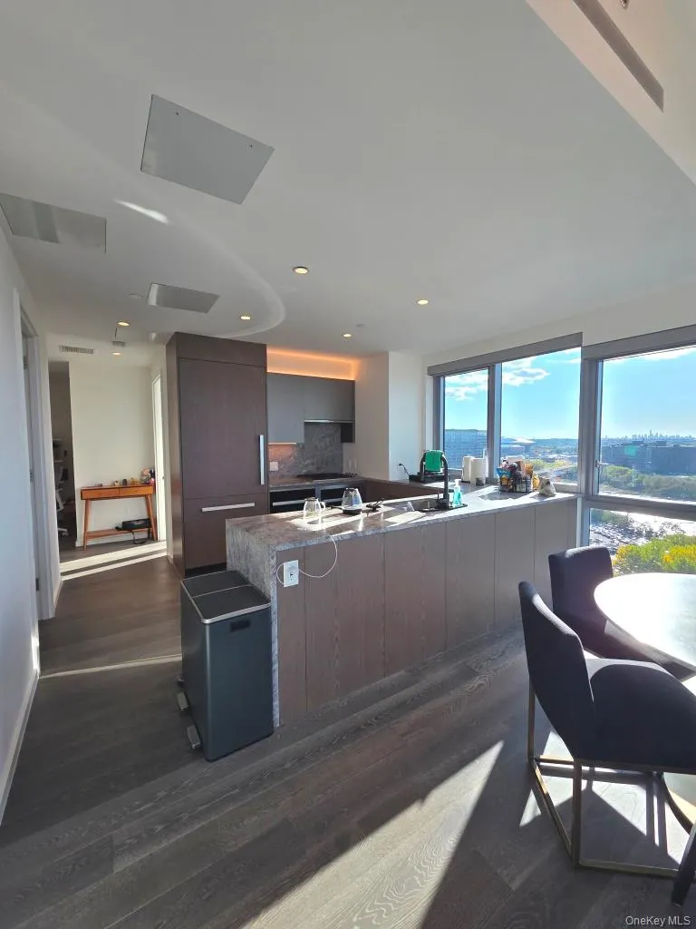 Kitchen with modern cabinets, dark wood-style floors, decorative backsplash, a peninsula, and recessed lighting Kitchen with modern cabinets, dark wood-style floors, decorative backsplash, a peninsula, and recessed lighting