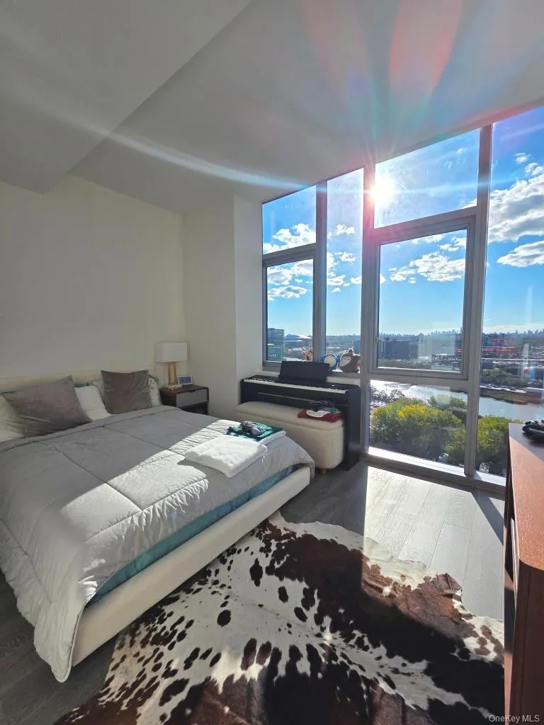 Bedroom featuring wood finished floors and expansive windows Bedroom featuring wood finished floors and expansive windows