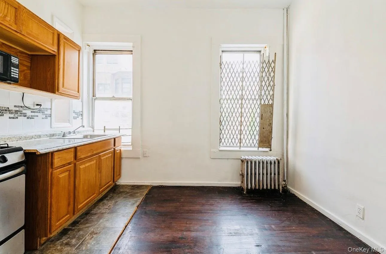 Kitchen featuring brown cabinetry, plenty of natural light, light countertops, and radiator heating unit Kitchen featuring brown cabinetry, plenty of natural light, light countertops, and radiator heating unit