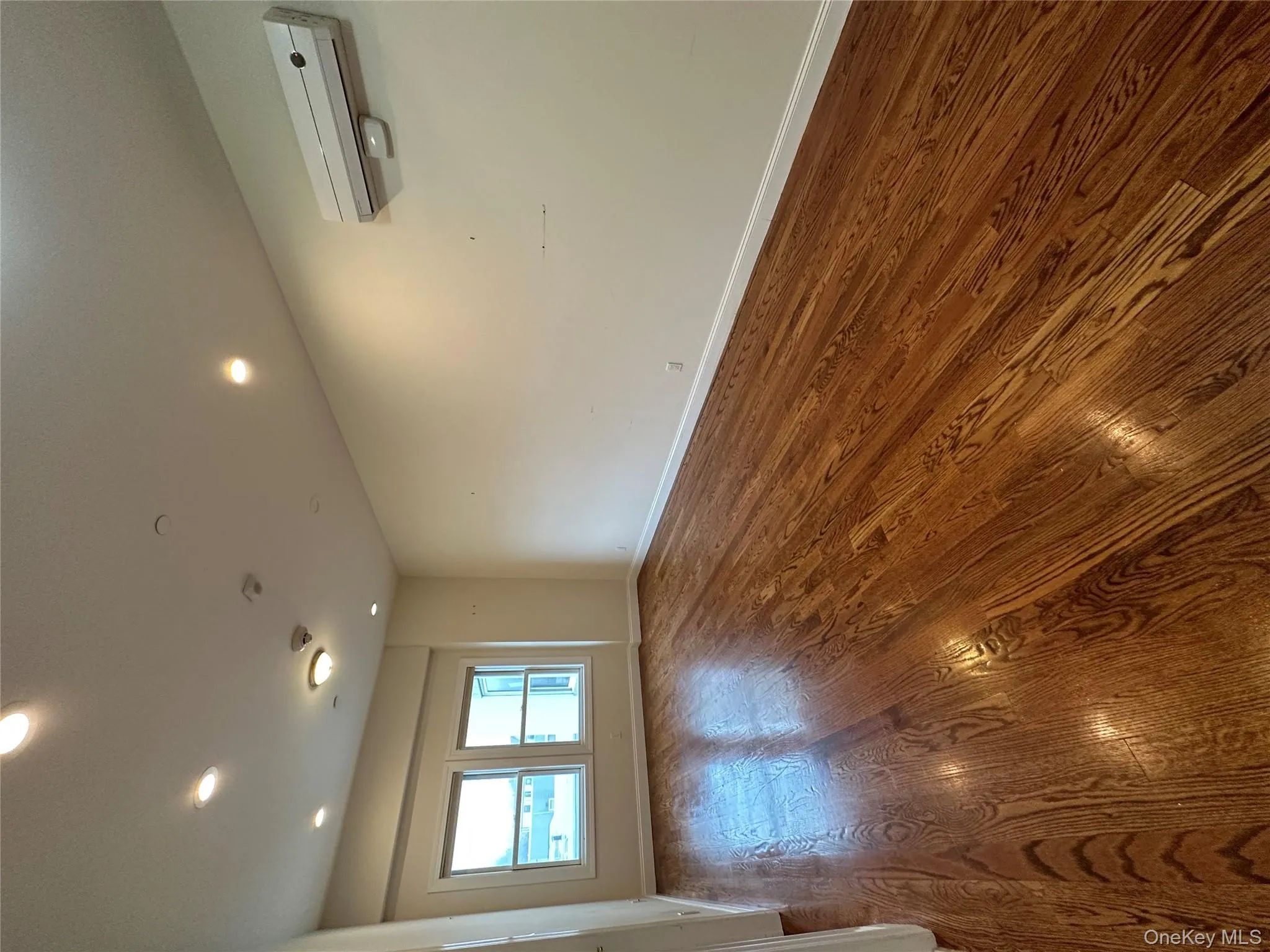 Empty room with dark wood finished floors, a wall mounted AC, and recessed lighting Empty room with dark wood finished floors, a wall mounted AC, and recessed lighting