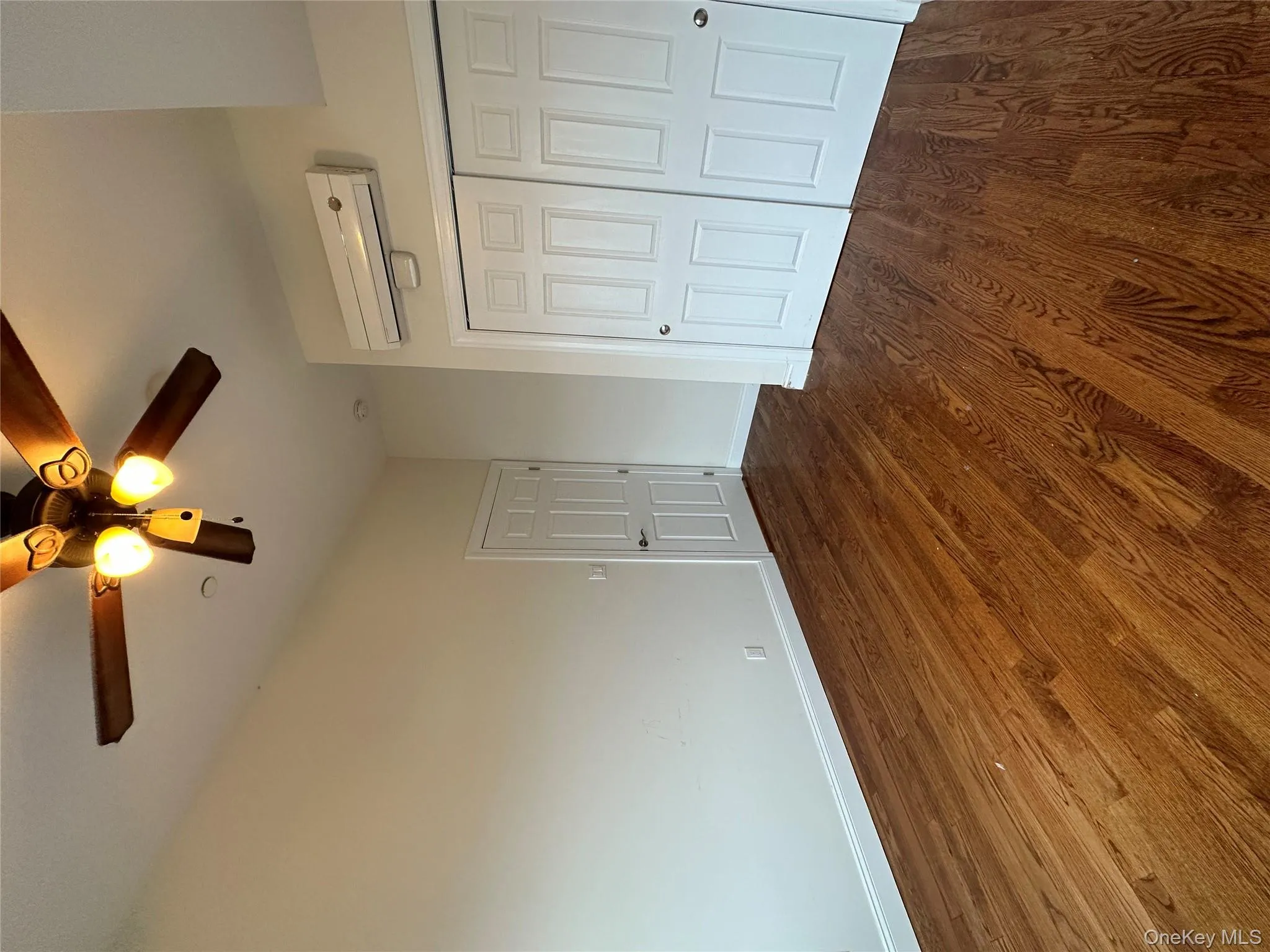 Unfurnished bedroom with dark wood finished floors, ceiling fan, a closet, and a wall unit AC Unfurnished bedroom with dark wood finished floors, ceiling fan, a closet, and a wall unit AC