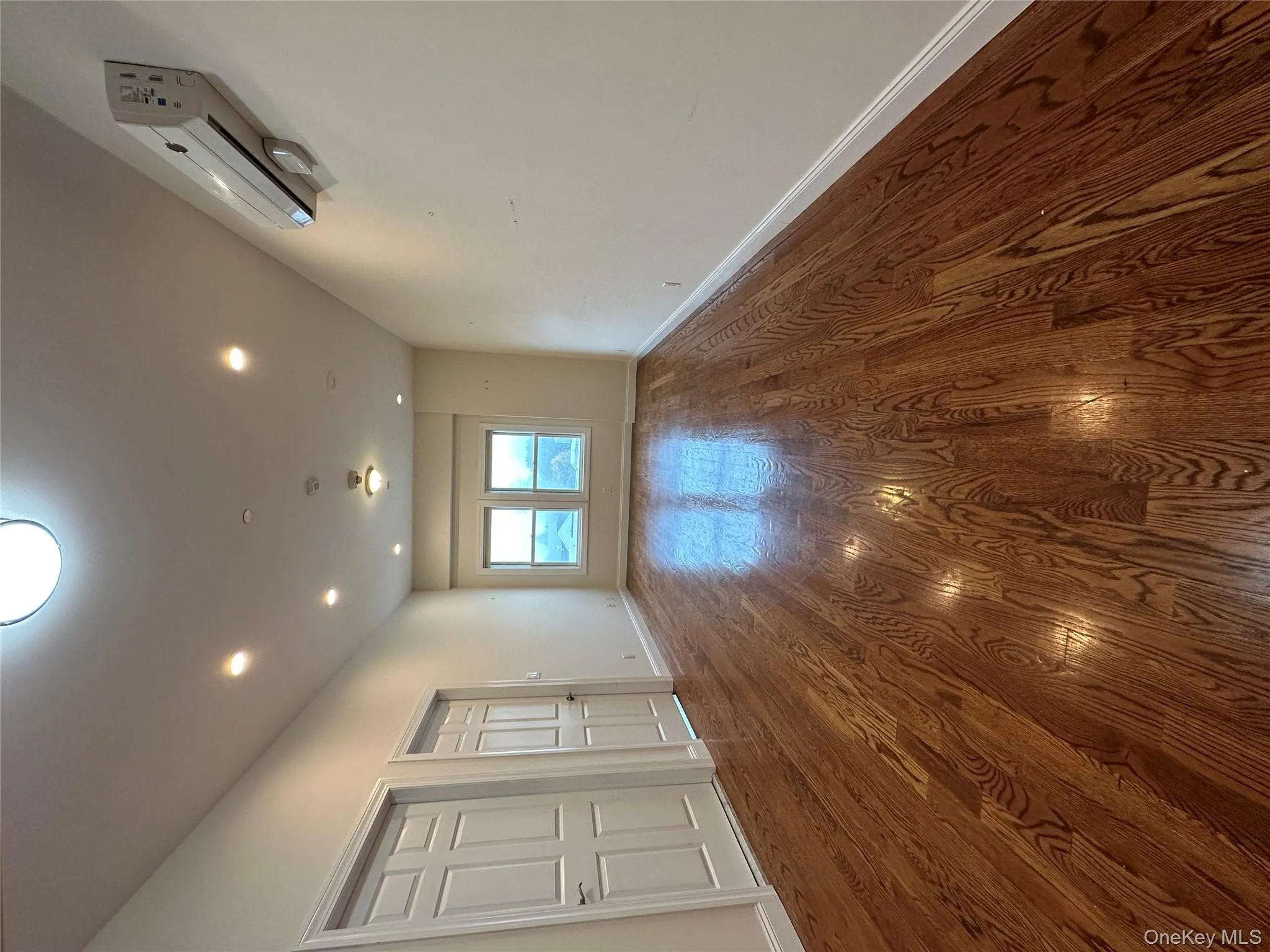 Empty room featuring dark wood-style flooring, an AC wall unit, and recessed lighting Empty room featuring dark wood-style flooring, an AC wall unit, and recessed lighting
