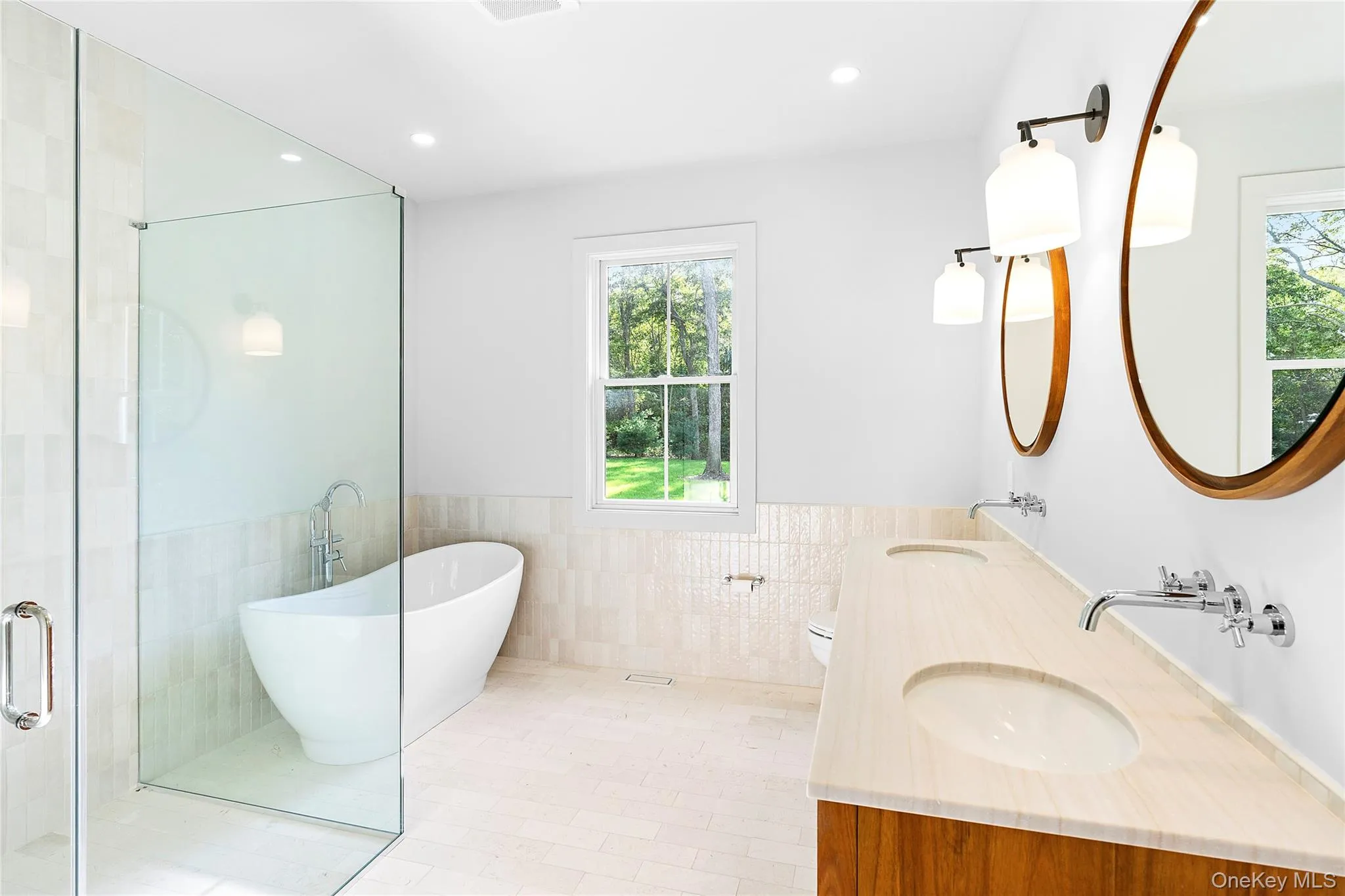 Primary bathroom with tile walls, a soaking tub, plenty of natural light, a wainscoted wall, and a shower stall Primary bathroom with tile walls, a soaking tub, plenty of natural light, a wainscoted wall, and a shower stall