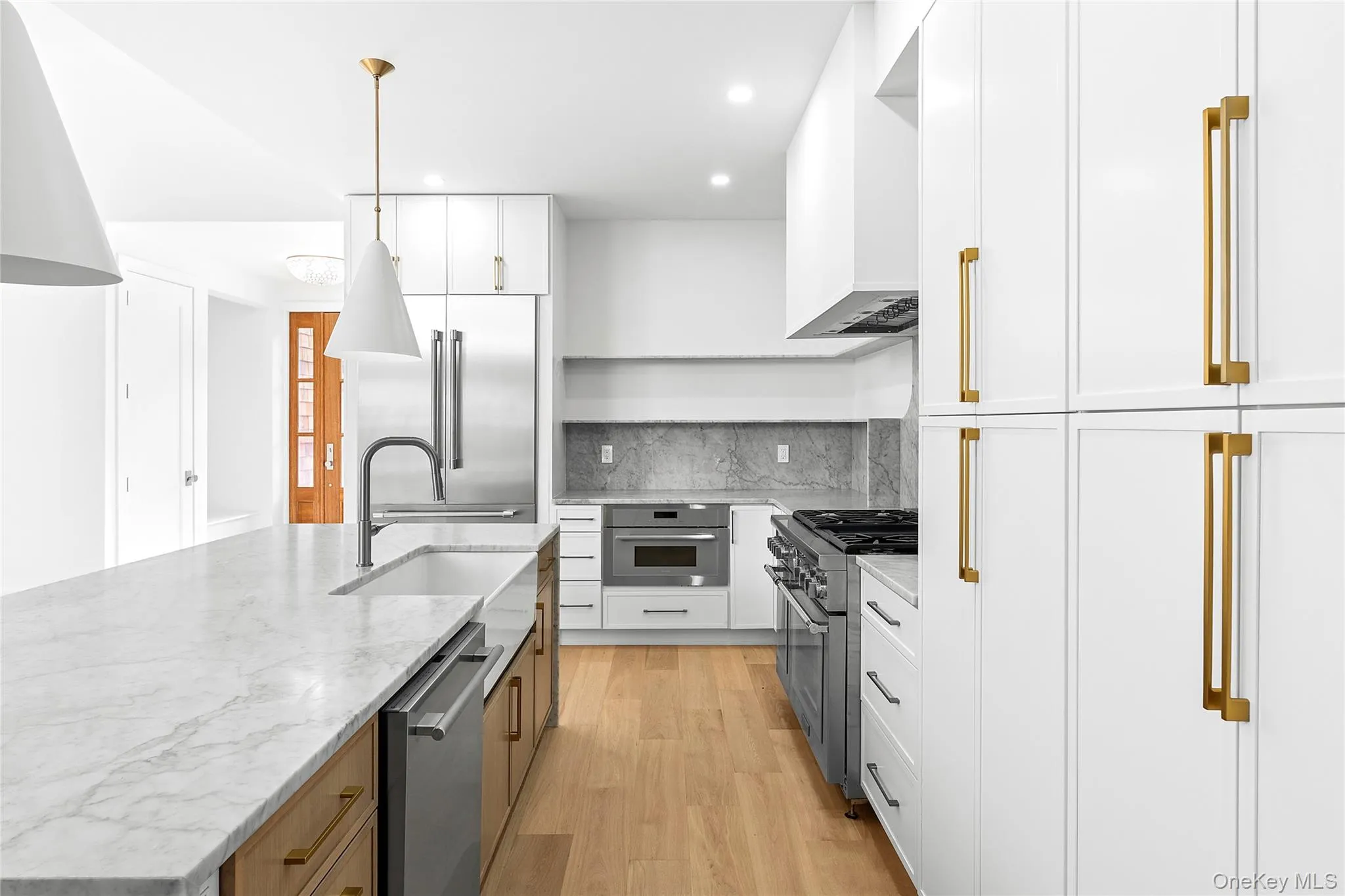 Kitchen with white cabinetry, a center island with sink, light stone countertops, light wood-style flooring, and hanging light fixtures Kitchen with white cabinetry, a center island with sink, light stone countertops, light wood-style flooring, and hanging light fixtures