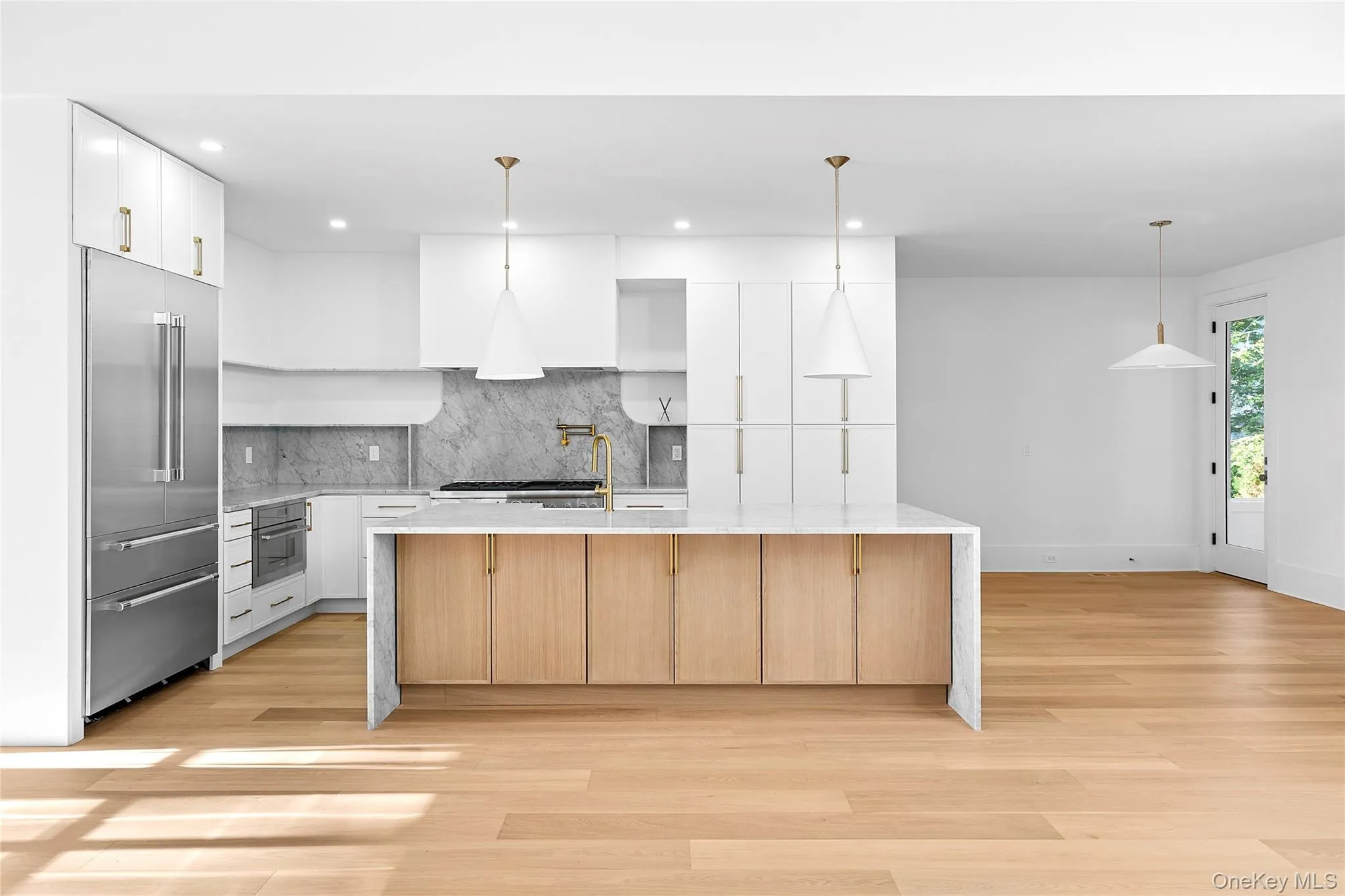 Kitchen featuring white cabinetry, hanging light fixtures, light stone counters, backsplash, and appliances with stainless steel finishes Kitchen featuring white cabinetry, hanging light fixtures, light stone counters, backsplash, and appliances with stainless steel finishes