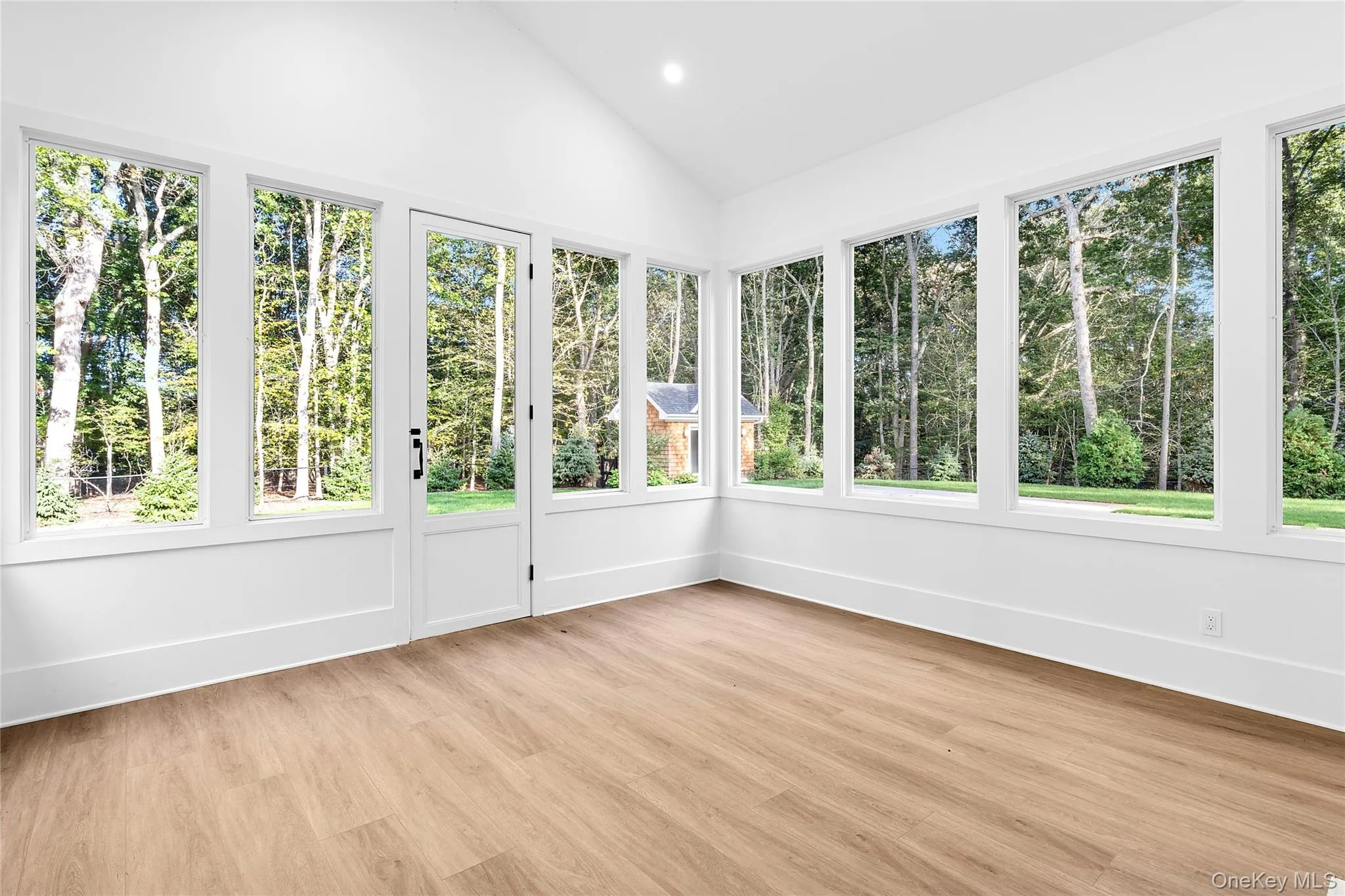 Sunroom featuring wood finished floors, vaulted ceiling, and recessed lighting Sunroom featuring wood finished floors, vaulted ceiling, and recessed lighting