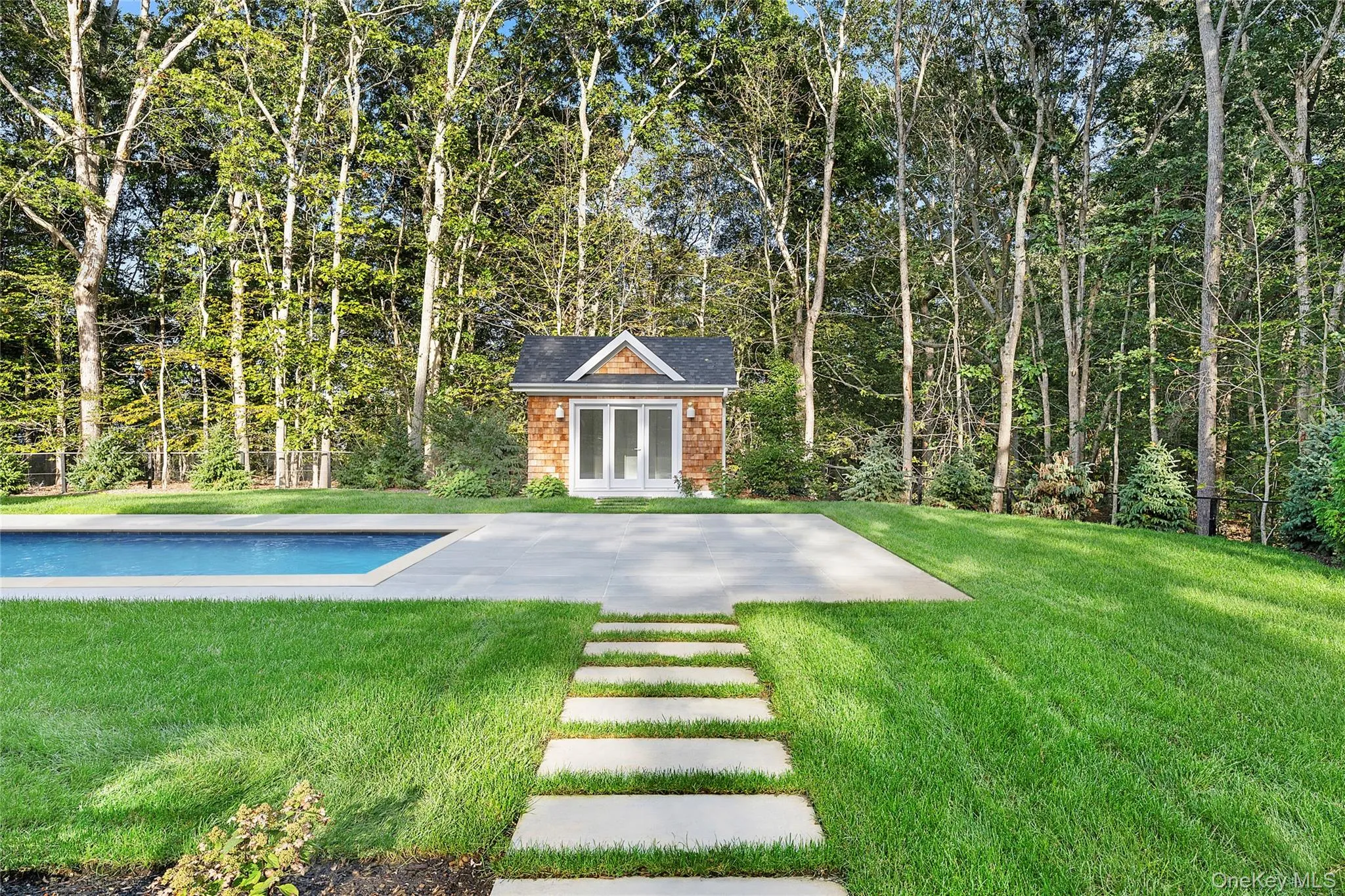Outdoor pool with a pool house and a yard Outdoor pool with a pool house and a yard