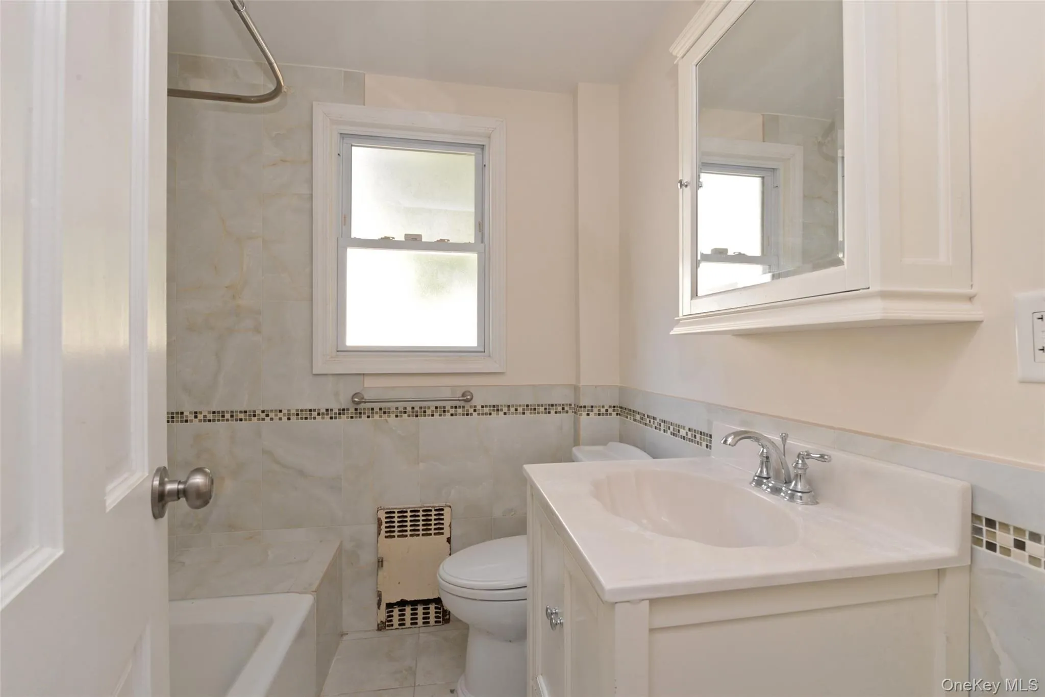 Bathroom featuring vanity, tile walls, radiator, washtub / shower combination, and light tile patterned floors Bathroom featuring vanity, tile walls, radiator, washtub / shower combination, and light tile patterned floors
