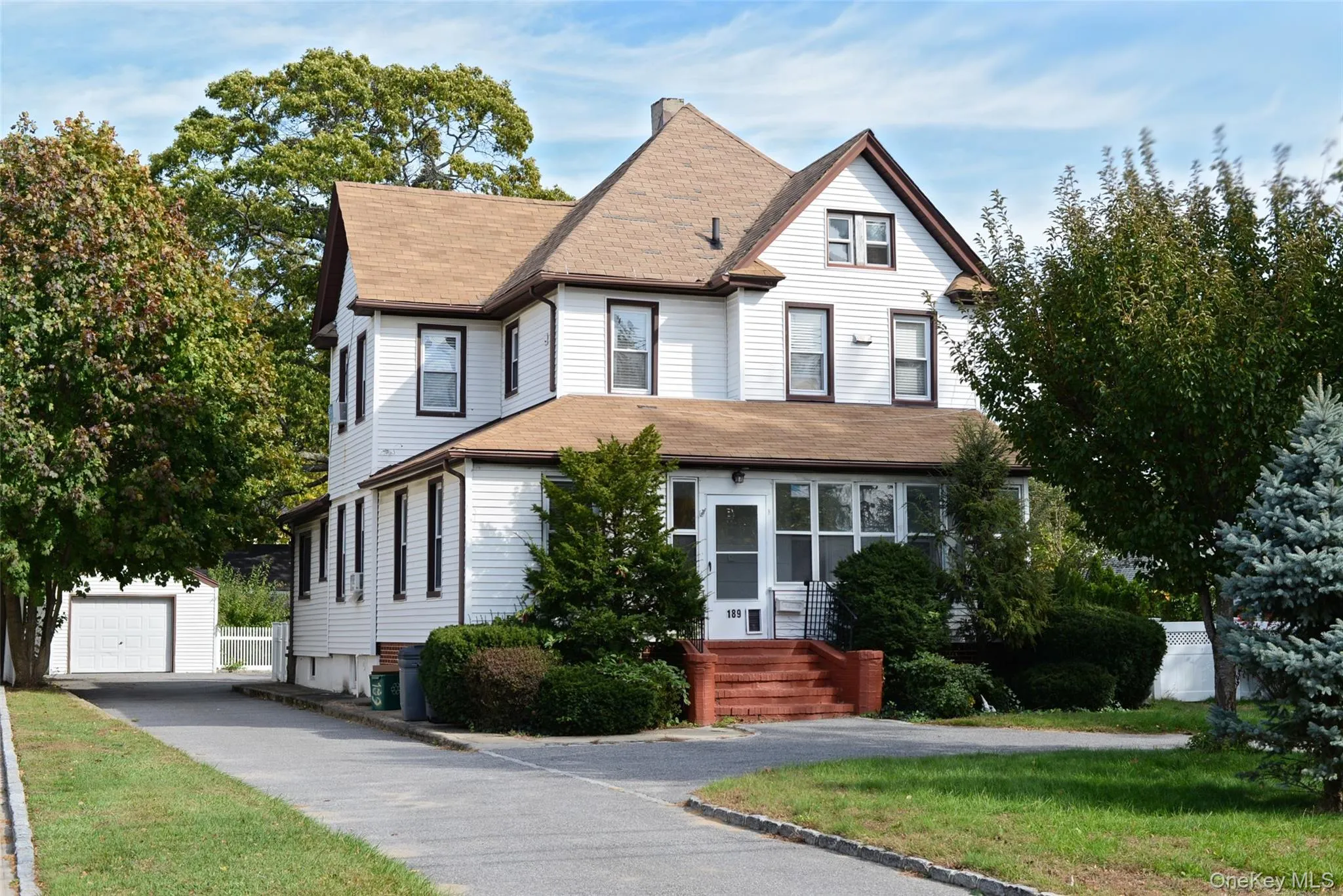 Victorian-style house featuring an outbuilding, roof with shingles, a detached garage, and driveway Victorian-style house featuring an outbuilding, roof with shingles, a detached garage, and driveway