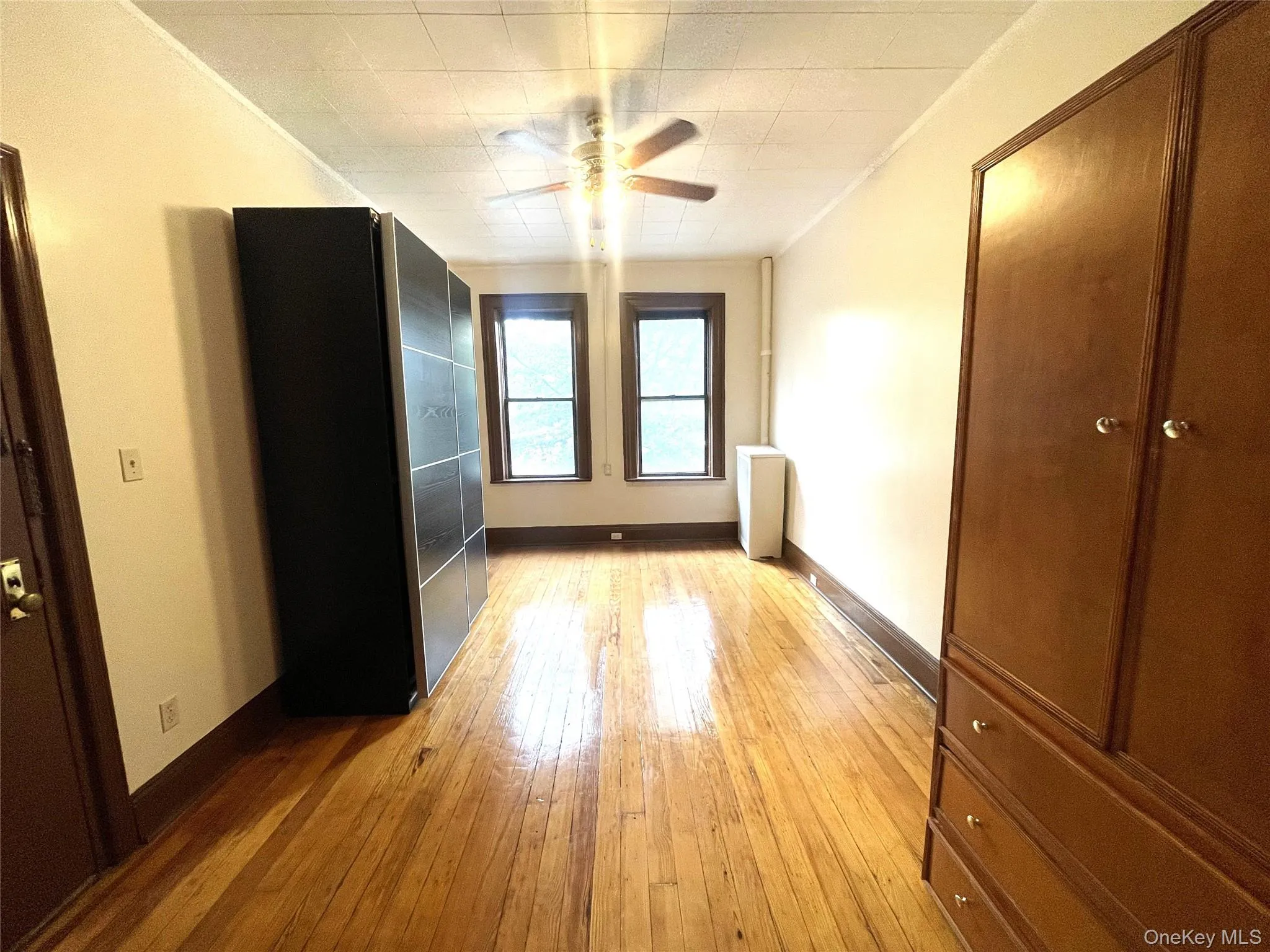 Unfurnished bedroom with light wood-style floors, ceiling fan, and ornamental molding Unfurnished bedroom with light wood-style floors, ceiling fan, and ornamental molding