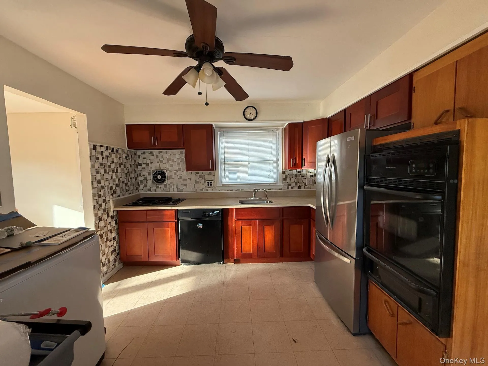 Kitchen with decorative backsplash, light countertops, a warming drawer, black appliances, and ceiling fan Kitchen with decorative backsplash, light countertops, a warming drawer, black appliances, and ceiling fan