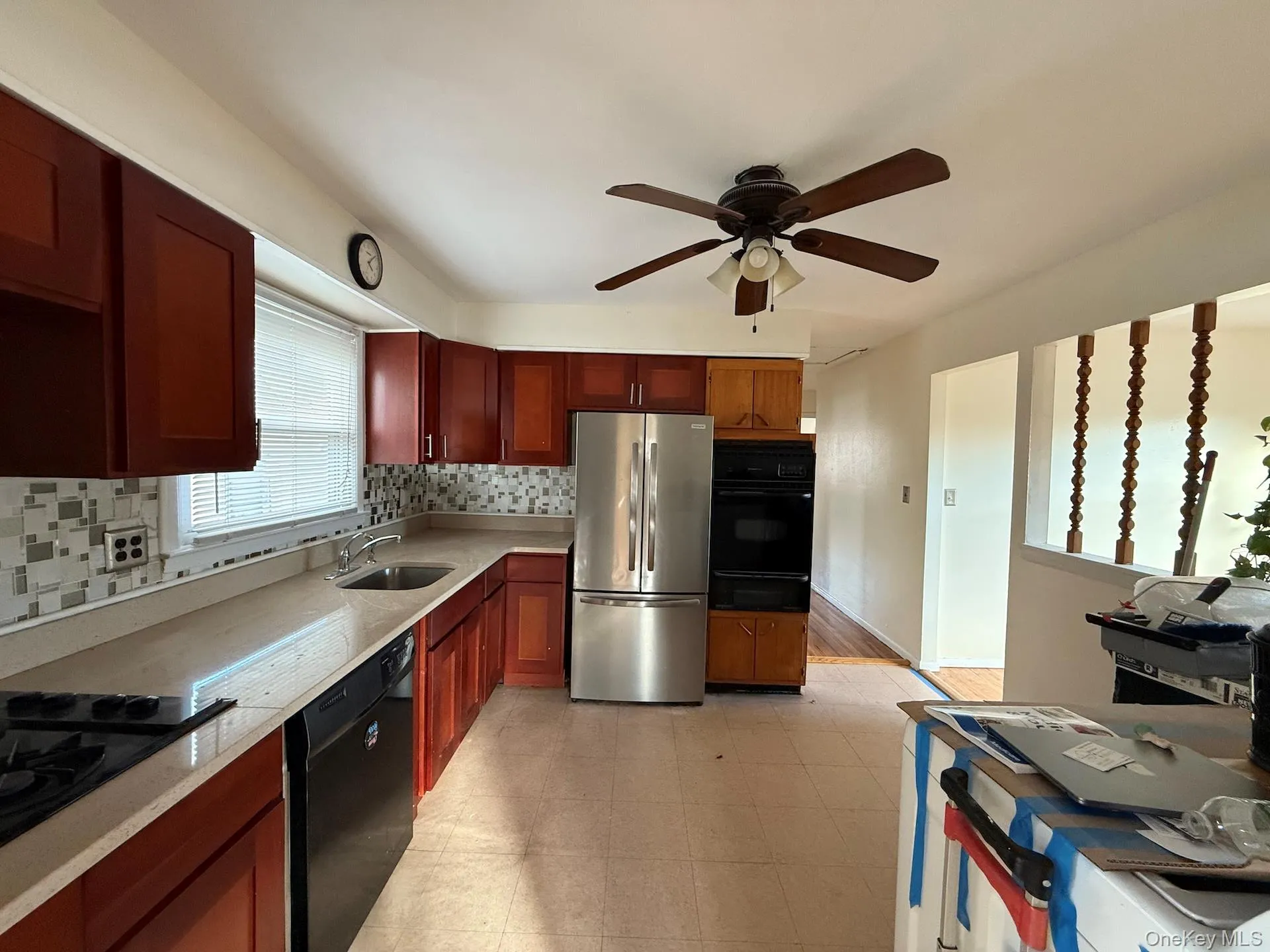 Kitchen with black appliances, backsplash, light stone counters, a warming drawer, and ceiling fan Kitchen with black appliances, backsplash, light stone counters, a warming drawer, and ceiling fan