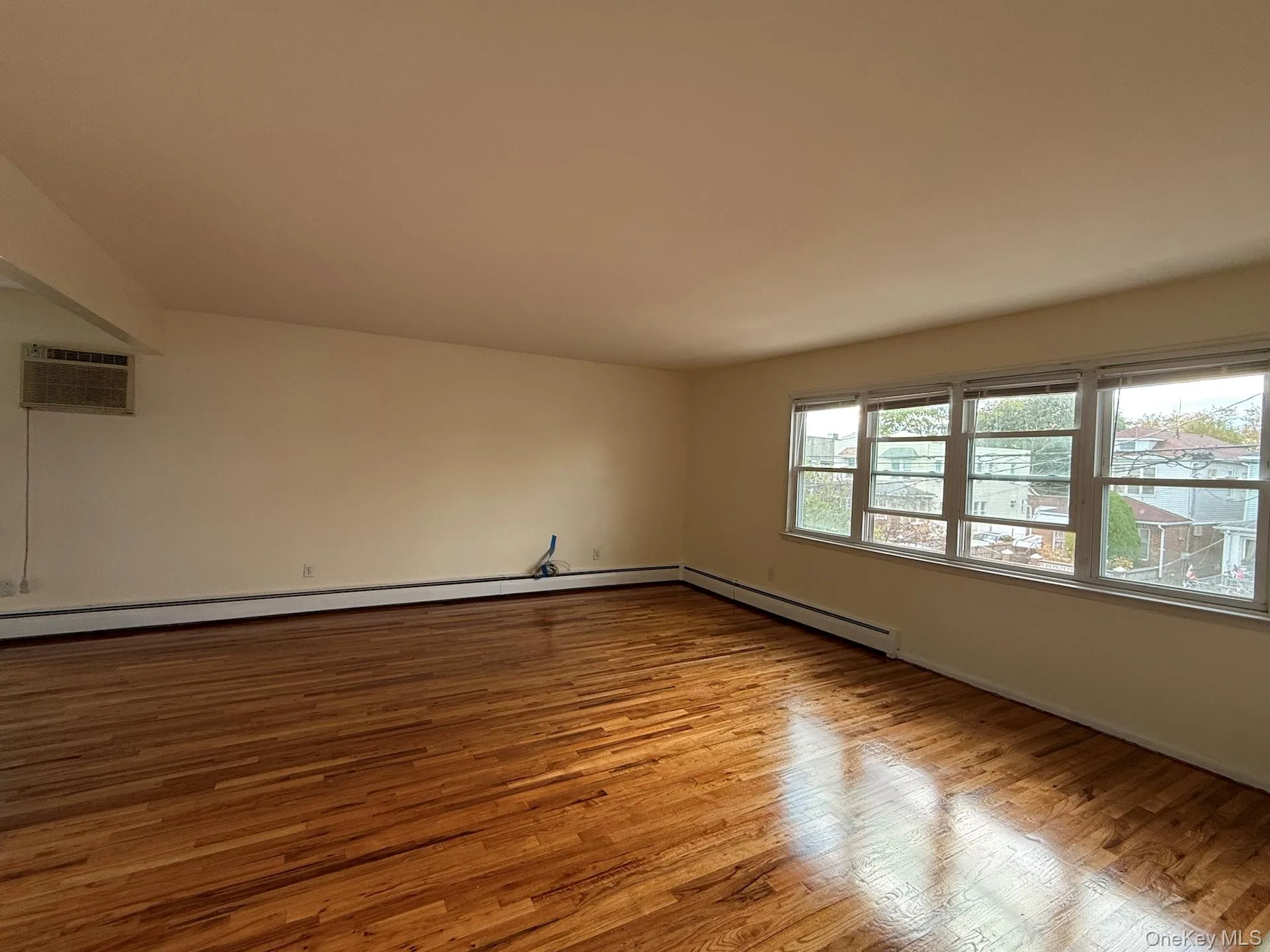 Spare room featuring light wood finished floors, a wall mounted air conditioner, and baseboard heating Spare room featuring light wood finished floors, a wall mounted air conditioner, and baseboard heating