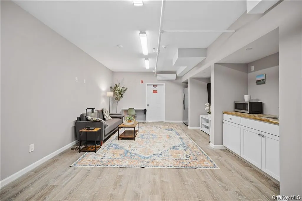 Living room featuring light wood-type flooring and a wall mounted air conditioner Living room featuring light wood-type flooring and a wall mounted air conditioner