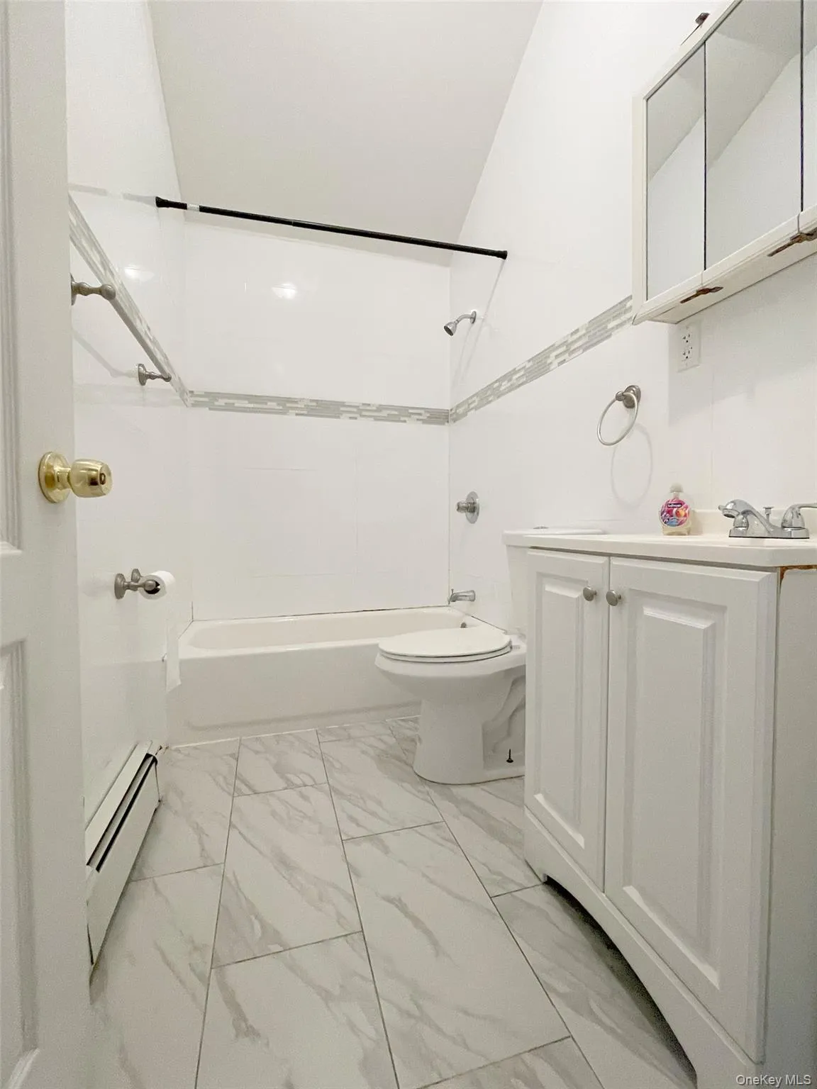 Full bath with shower / washtub combination, vanity, a baseboard radiator, and light marble finish flooring Full bath with shower / washtub combination, vanity, a baseboard radiator, and light marble finish flooring