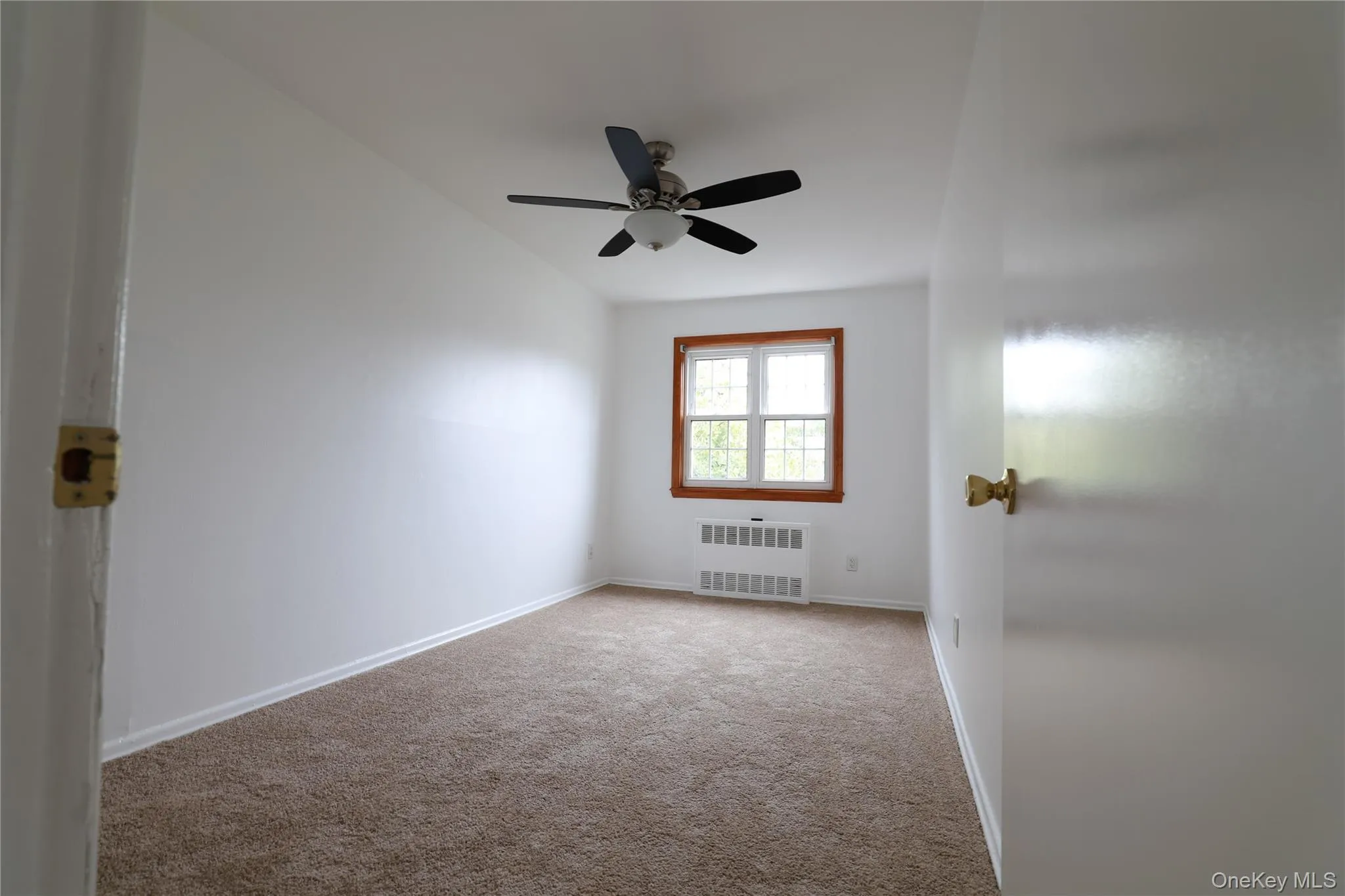 Bedroom featuring carpet flooring, radiator, and a ceiling fan Bedroom featuring carpet flooring, radiator, and a ceiling fan
