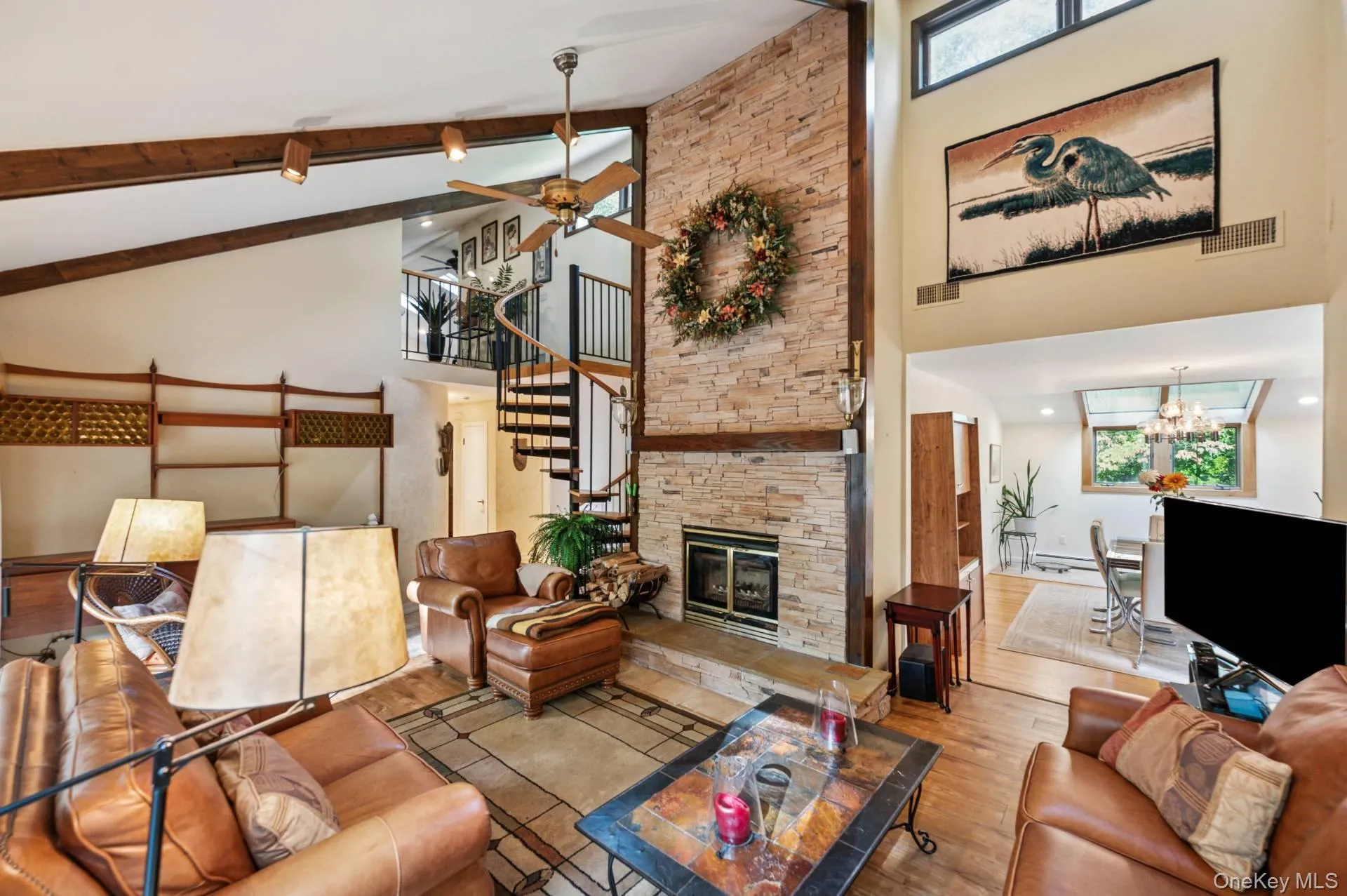 Living room featuring a chandelier, high vaulted ceiling, beam ceiling, hardwood / wood-style flooring, and a fireplace Living room featuring a chandelier, high vaulted ceiling, beam ceiling, hardwood / wood-style flooring, and a fireplace