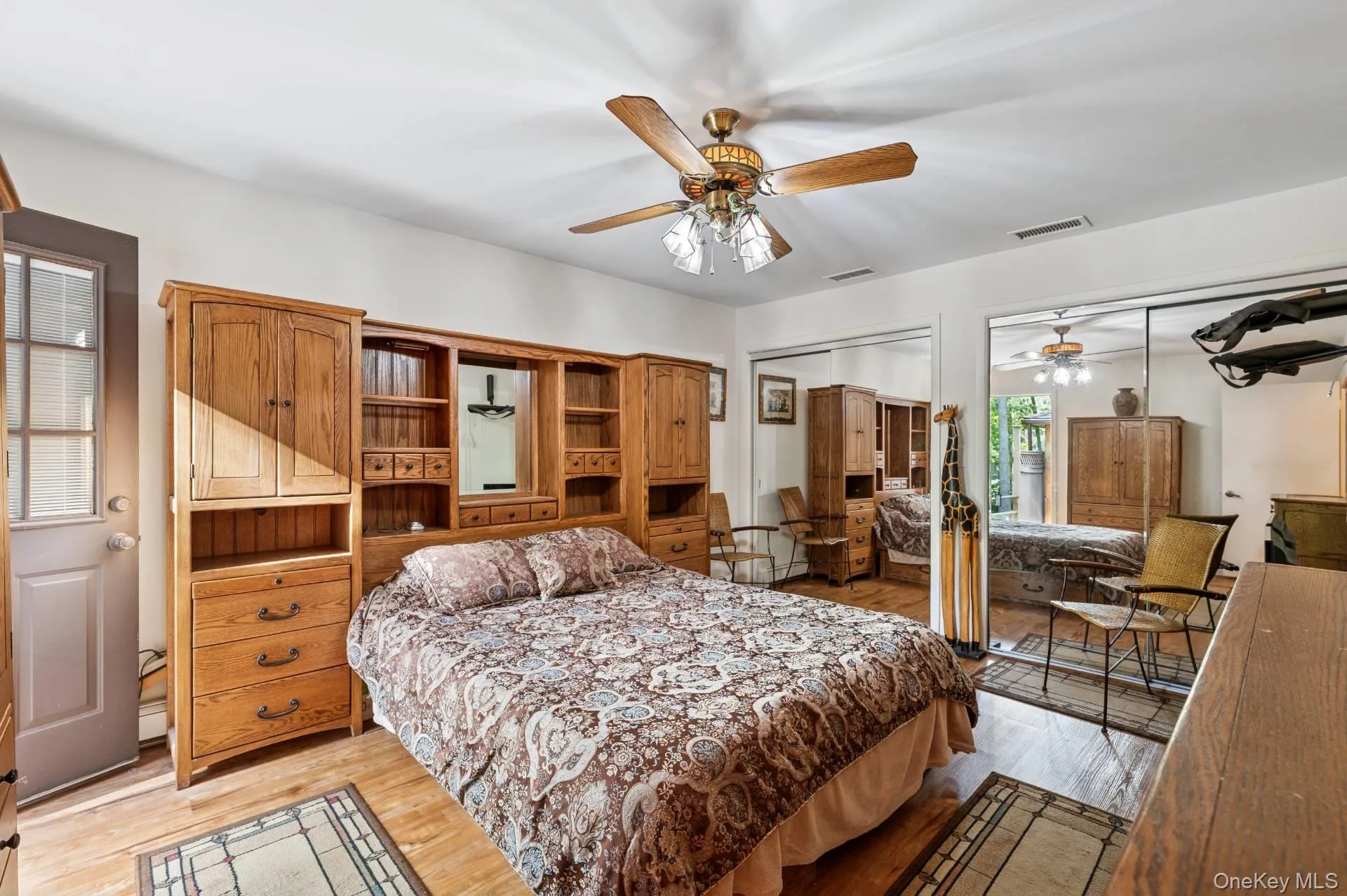 Bedroom with light wood-style flooring, ceiling fan, and multiple closets Bedroom with light wood-style flooring, ceiling fan, and multiple closets