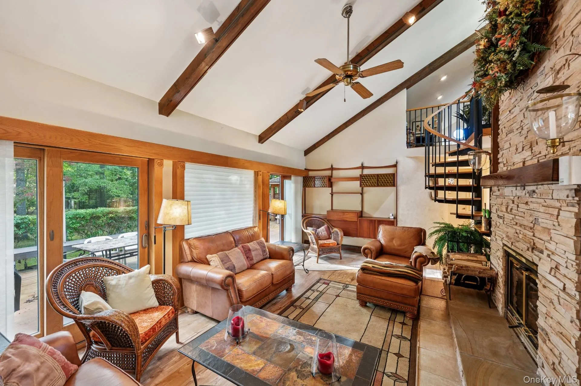 Living room featuring beam ceiling, high vaulted ceiling, a ceiling fan, stairway, and a fireplace Living room featuring beam ceiling, high vaulted ceiling, a ceiling fan, stairway, and a fireplace