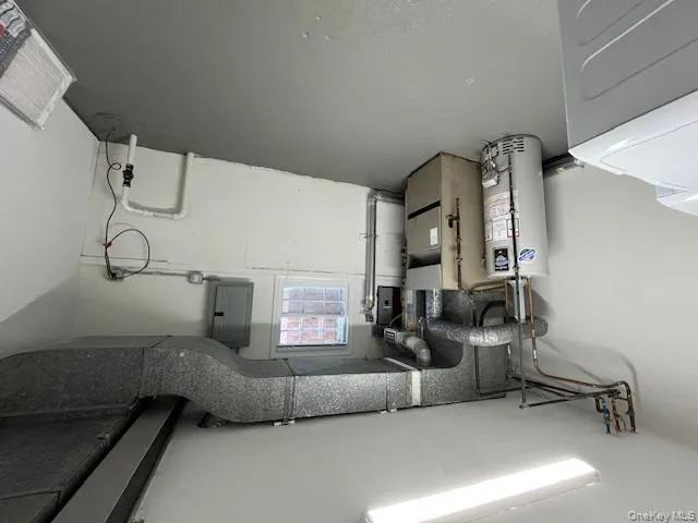 Basement featuring water heater, electric panel, and heating unit Basement featuring water heater, electric panel, and heating unit