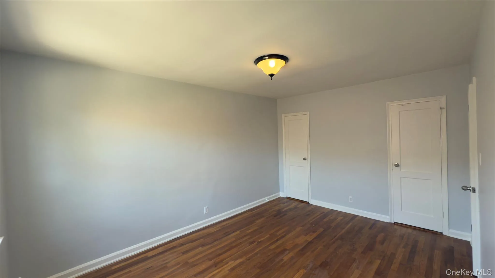 Unfurnished bedroom with dark wood finished floors and a closet Unfurnished bedroom with dark wood finished floors and a closet