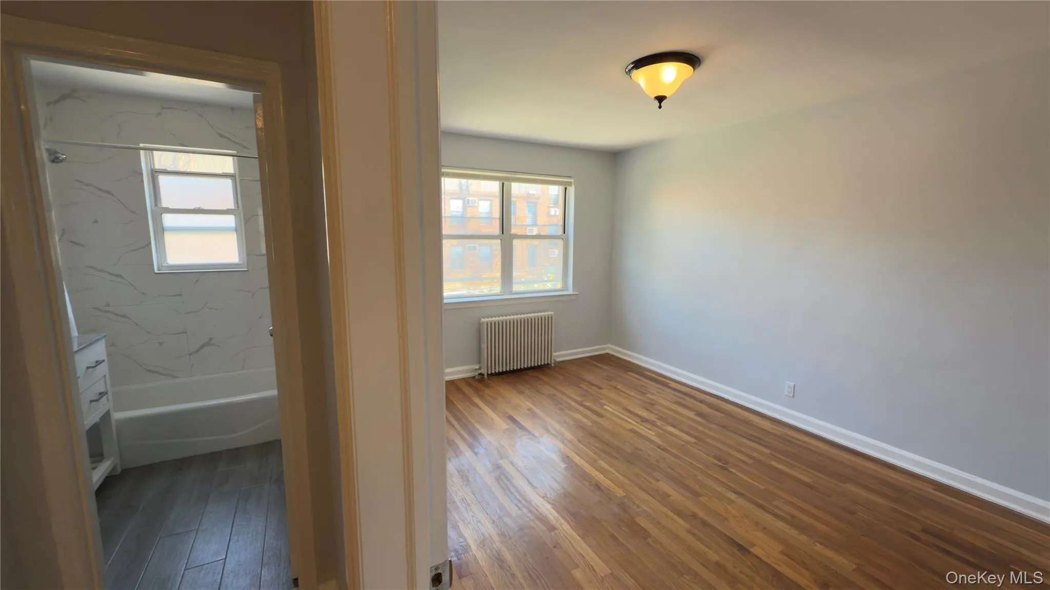 Spare room with healthy amount of natural light, radiator heating unit, and dark wood-type flooring Spare room with healthy amount of natural light, radiator heating unit, and dark wood-type flooring