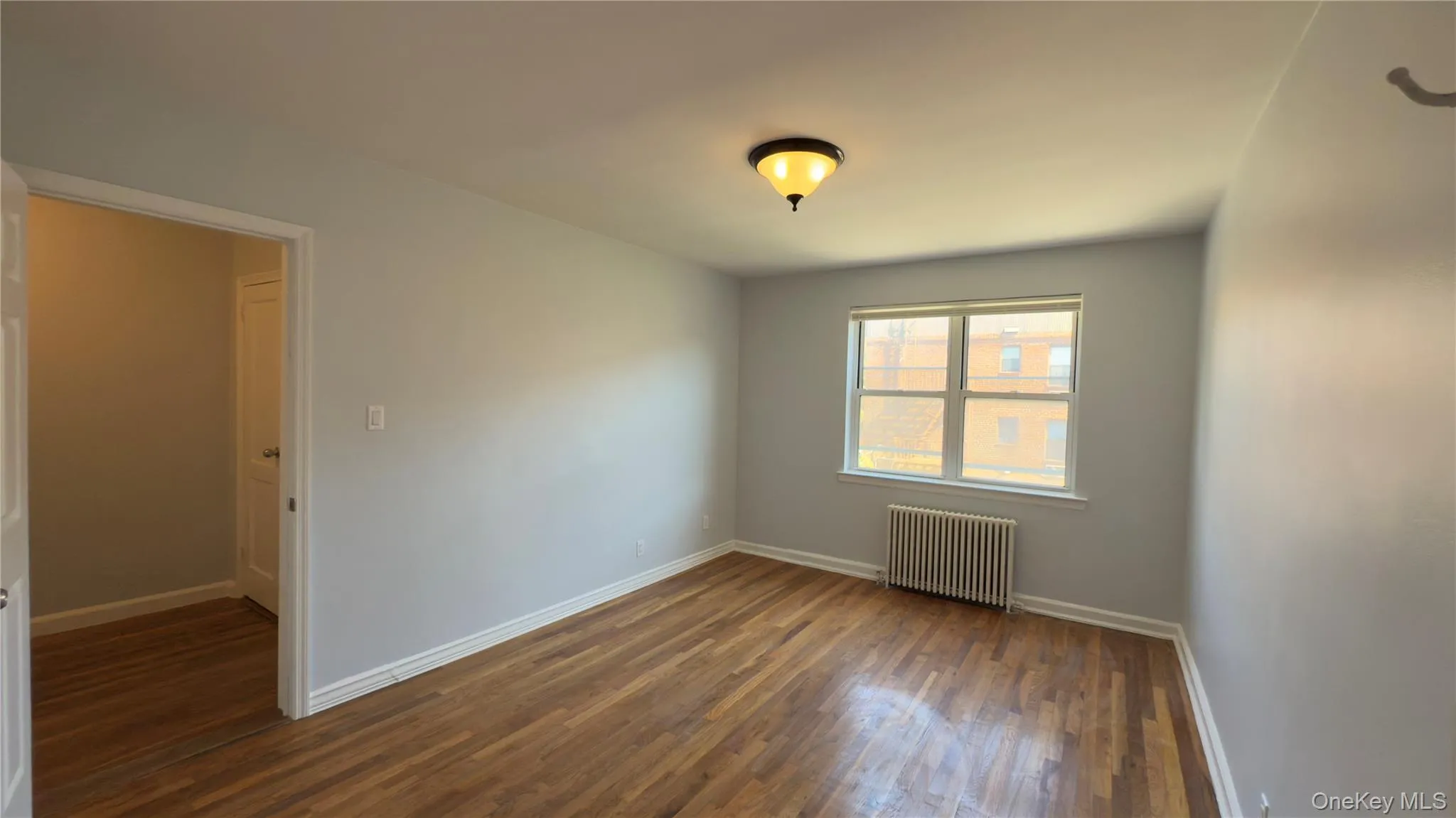 Spare room featuring radiator heating unit and dark wood-style flooring Spare room featuring radiator heating unit and dark wood-style flooring