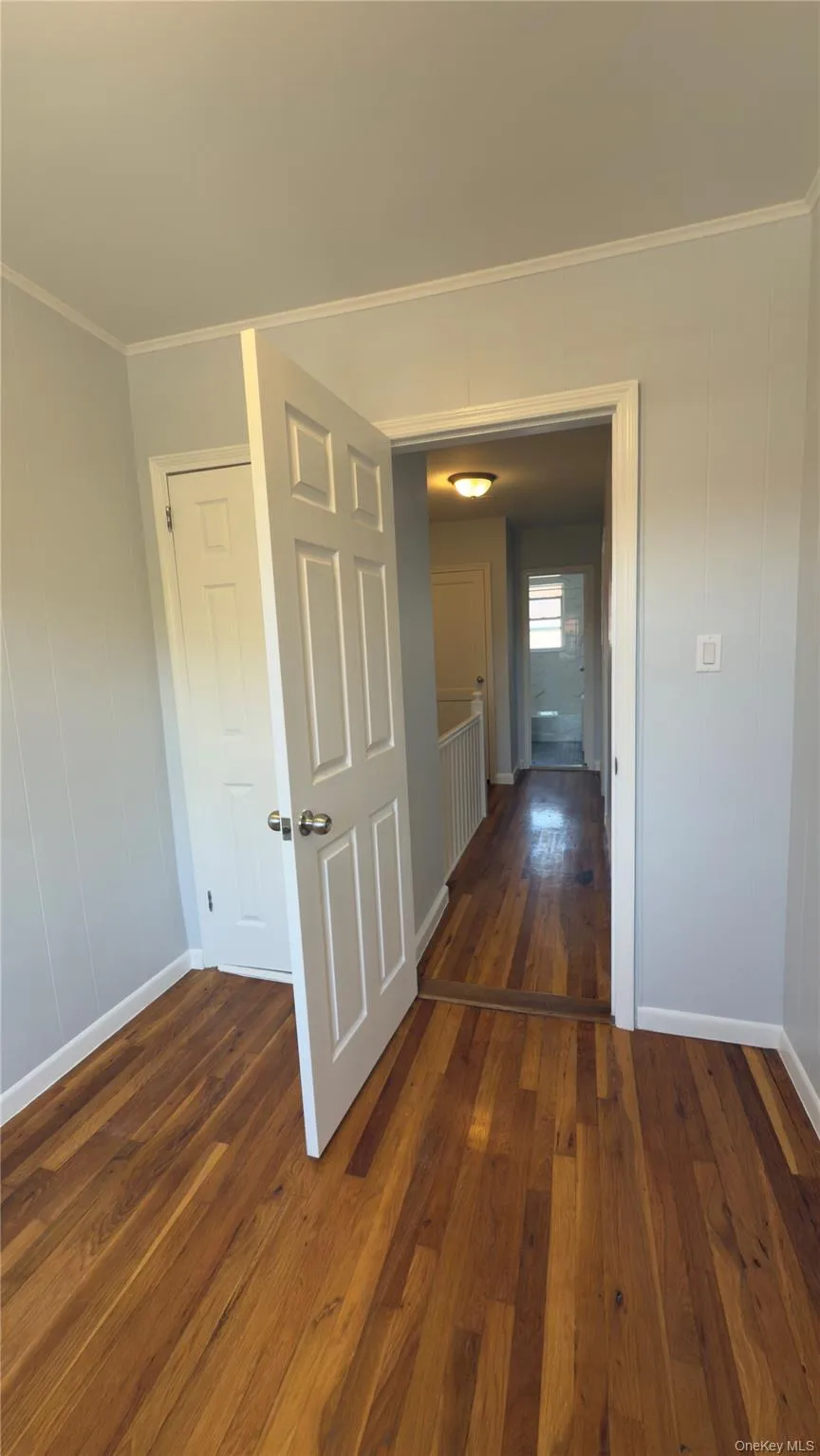 Hallway featuring dark wood finished floors and ornamental molding Hallway featuring dark wood finished floors and ornamental molding