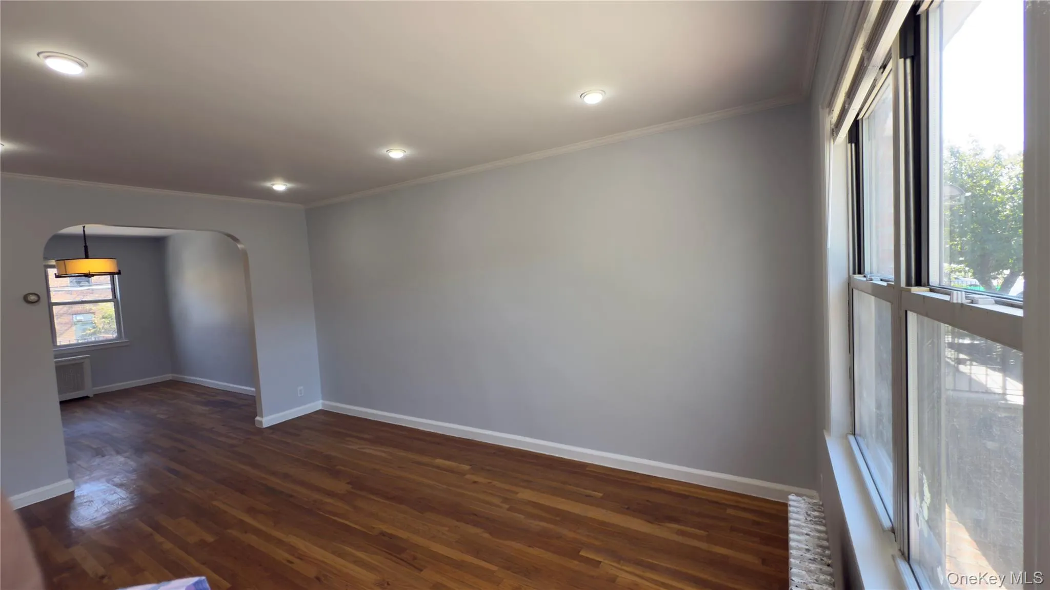 Spare room with dark wood-style floors, ornamental molding, arched walkways, and recessed lighting Spare room with dark wood-style floors, ornamental molding, arched walkways, and recessed lighting