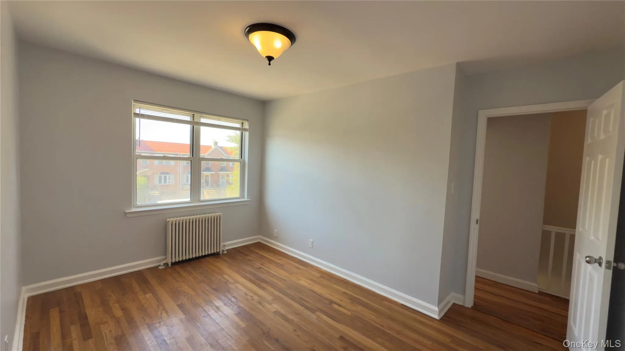 Spare room featuring radiator heating unit and hardwood / wood-style floors Spare room featuring radiator heating unit and hardwood / wood-style floors