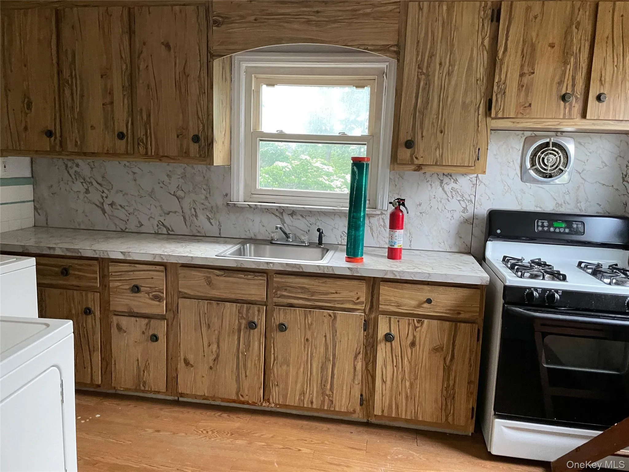 Kitchen with range with gas stovetop, light countertops, light wood finished floors, and decorative backsplash Kitchen with range with gas stovetop, light countertops, light wood finished floors, and decorative backsplash