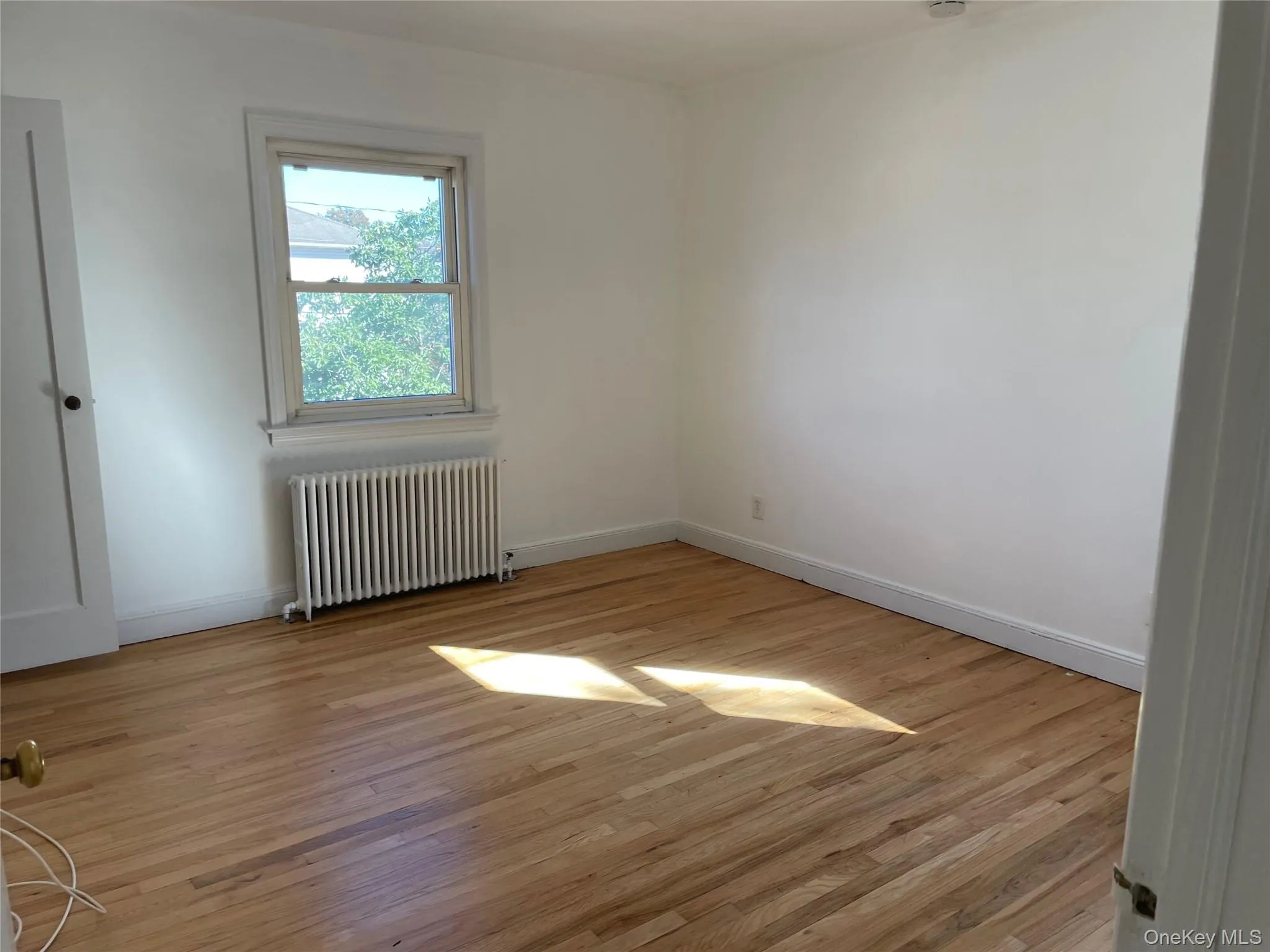 Empty room with radiator and light wood finished floors Empty room with radiator and light wood finished floors